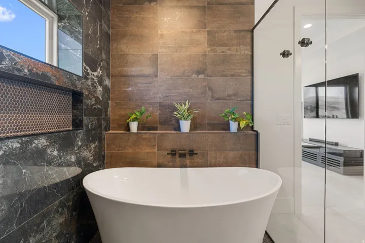Freestanding soaking tub with dark bronze wall-mounted fixtures in wetroom