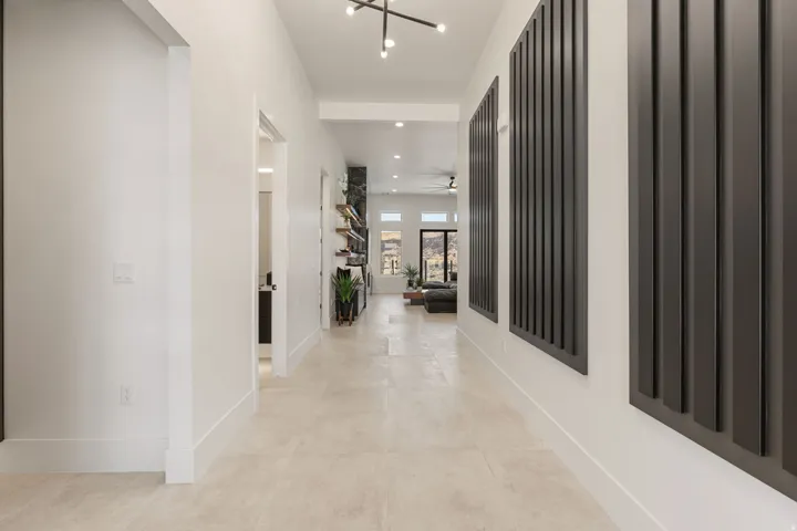 Long hallway featuring light-toned flooring, white walls, and dark decorative wall panels
