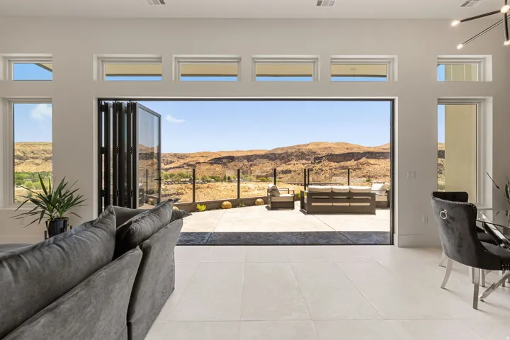 Expansive folding  glass doors open to a concrete patio with a clear railing and a beautiful view of Basalt Canyon and the Virgin River