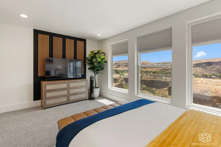 ADU bedroom featuring three large windows, recessed lighting, and a textured accent wall with vertical wood paneling