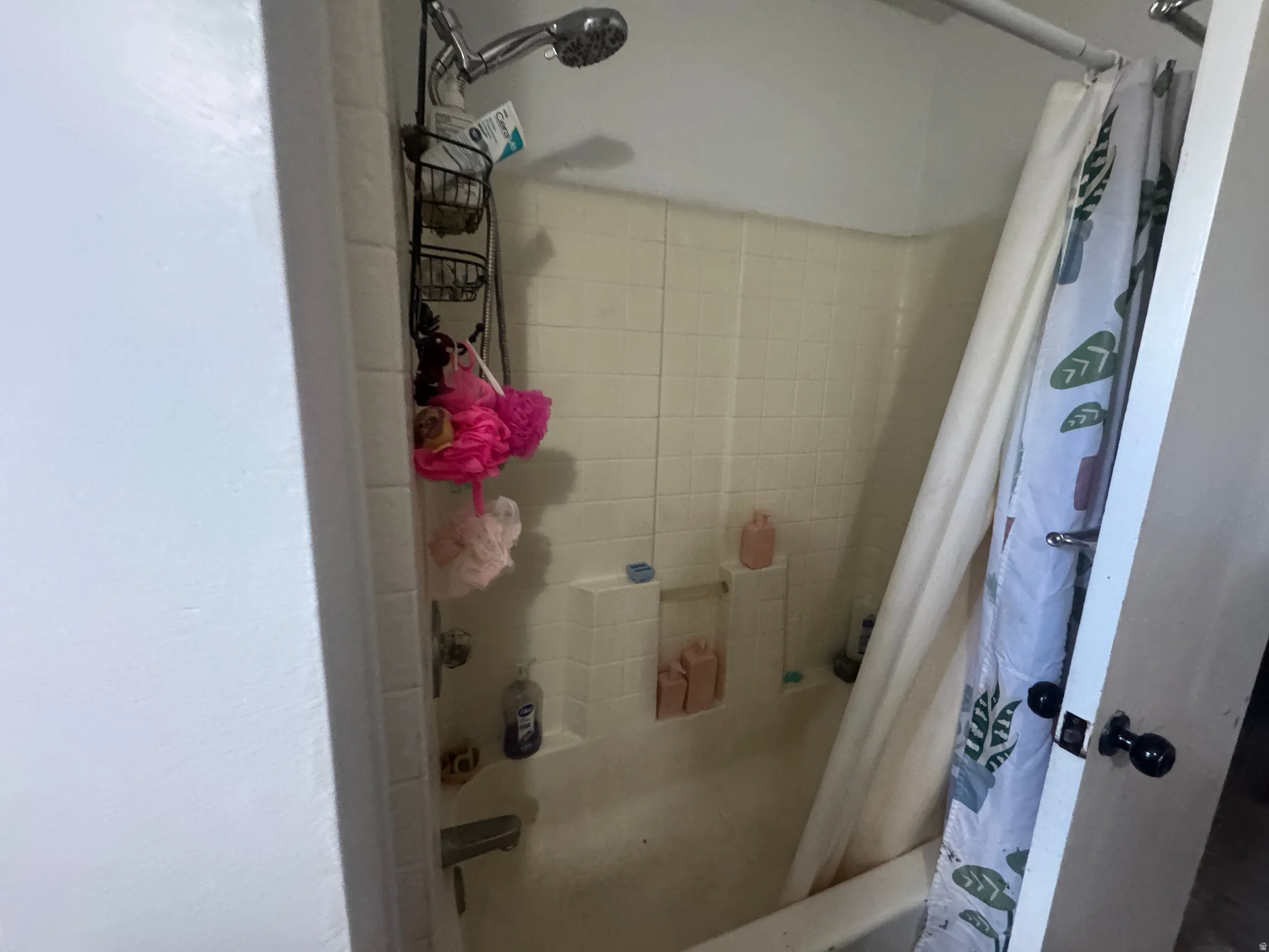 Bathtub and shower combination featuring tiled walls with integrated soap dishes and a chrome shower head