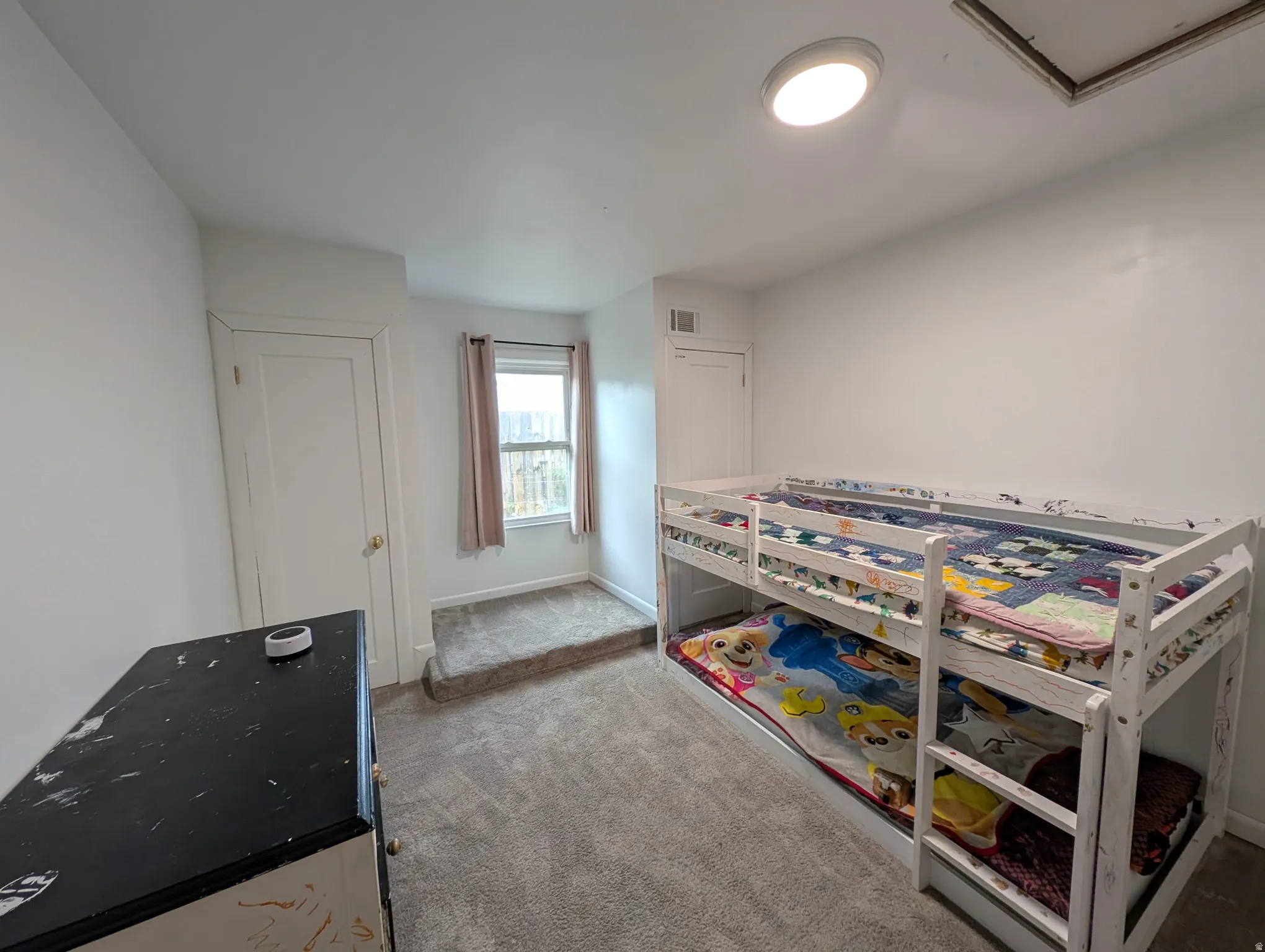 Carpeted flooring, white walls, flush-mount ceiling light, and window with natural light
