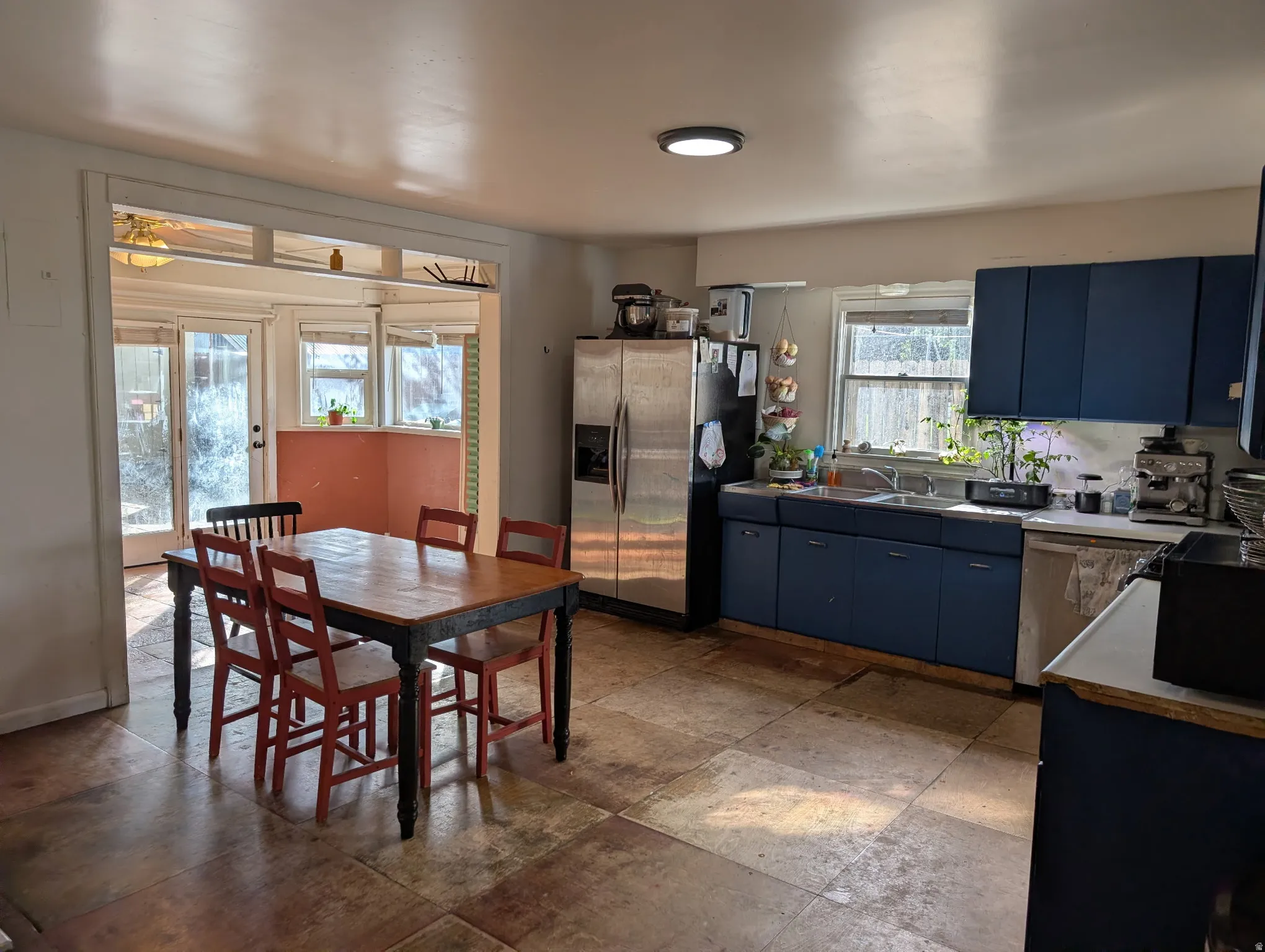 Kitchen space featuring blue base and upper cabinetry, a stainless steel refrigerator, and dual basin sink
