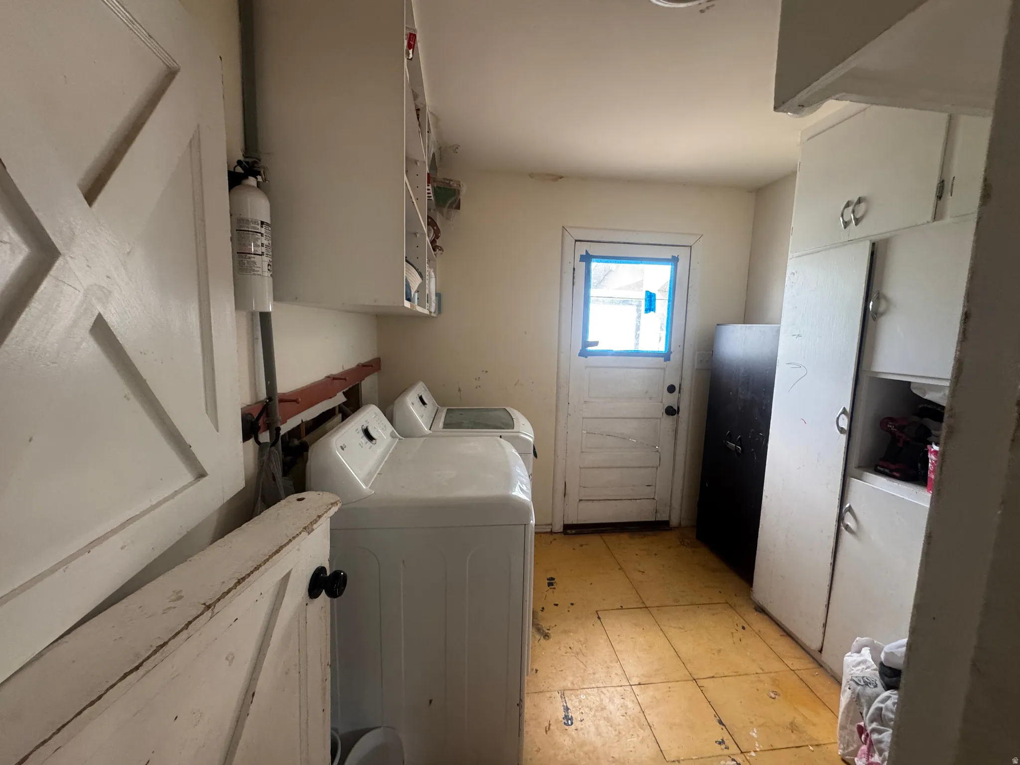 Utility room featuring a paneled door, built-in cabinetry, and wood-finish flooring
