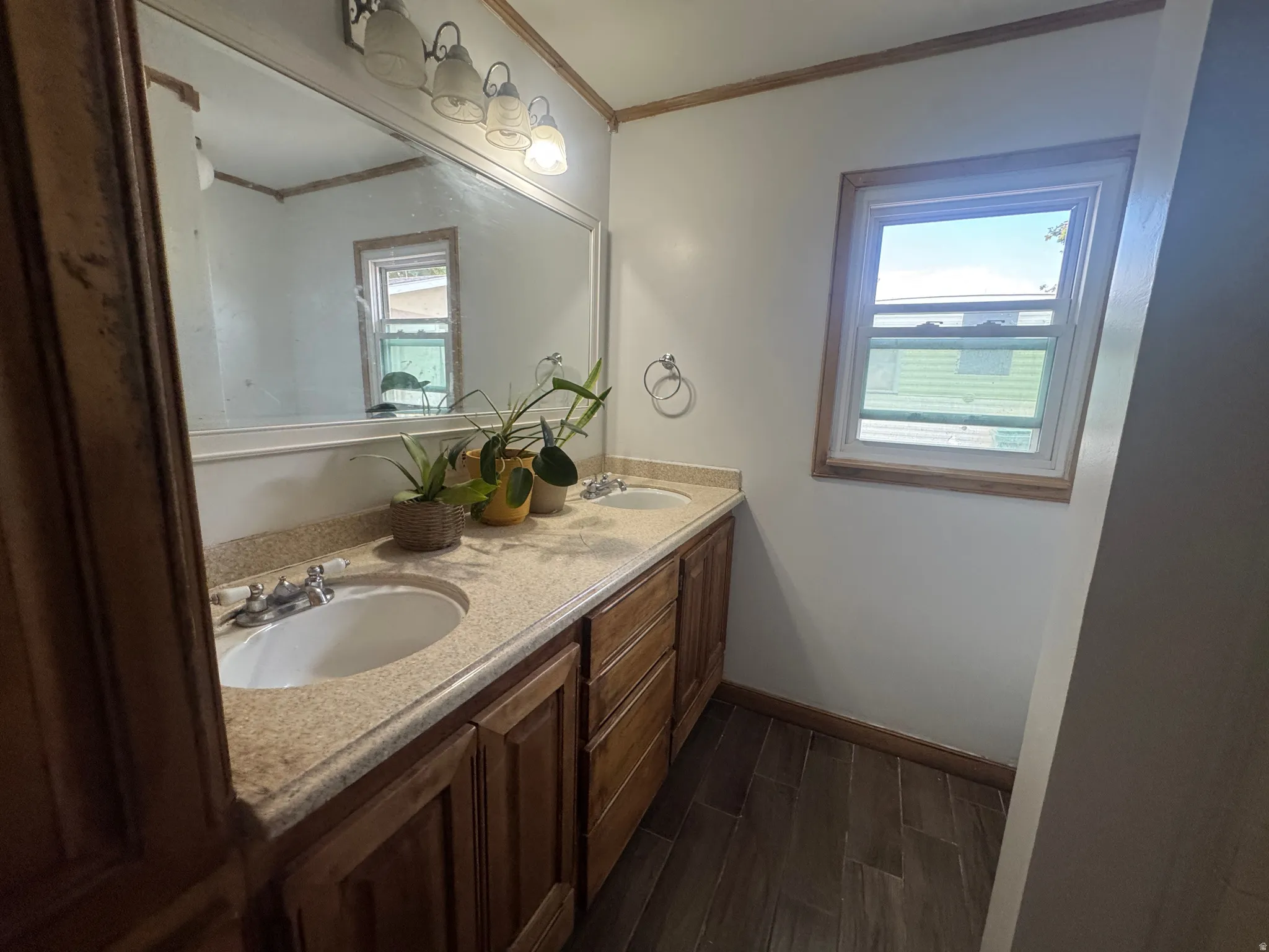 Double vanity with wood-finish cabinetry, integrated sinks, and a stone-look countertop