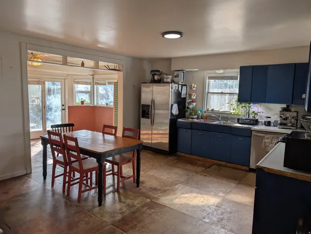 Kitchen space featuring blue base and upper cabinetry, a stainless steel refrigerator, and dual basin sink