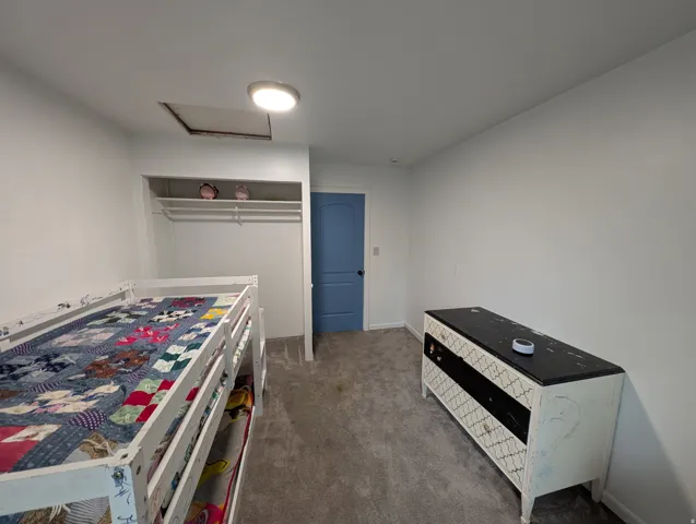 Wall-to-wall carpeting with an open closet featuring shelving and a hanging rod