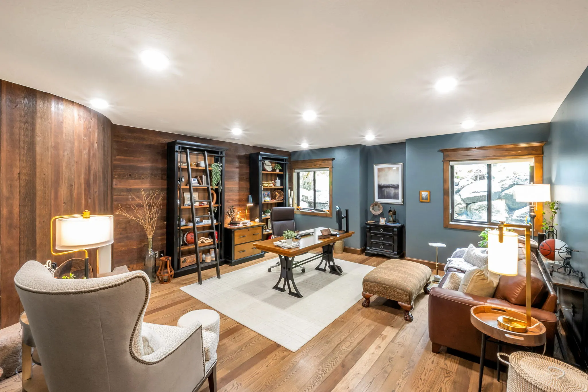 Expansive room featuring wood-finish flooring, a curved wood-panel accent wall, and recessed lighting