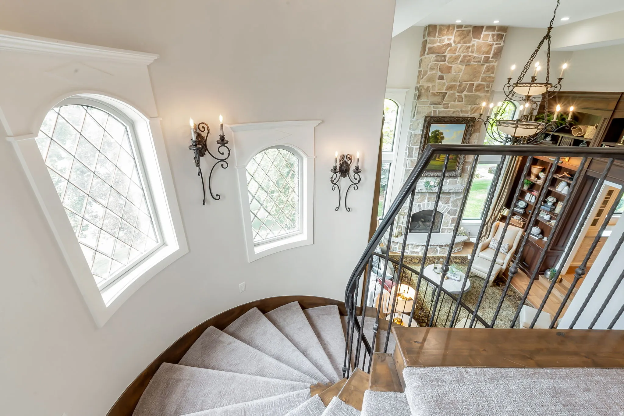 Curved staircase featuring carpeted treads and a wrought iron railing