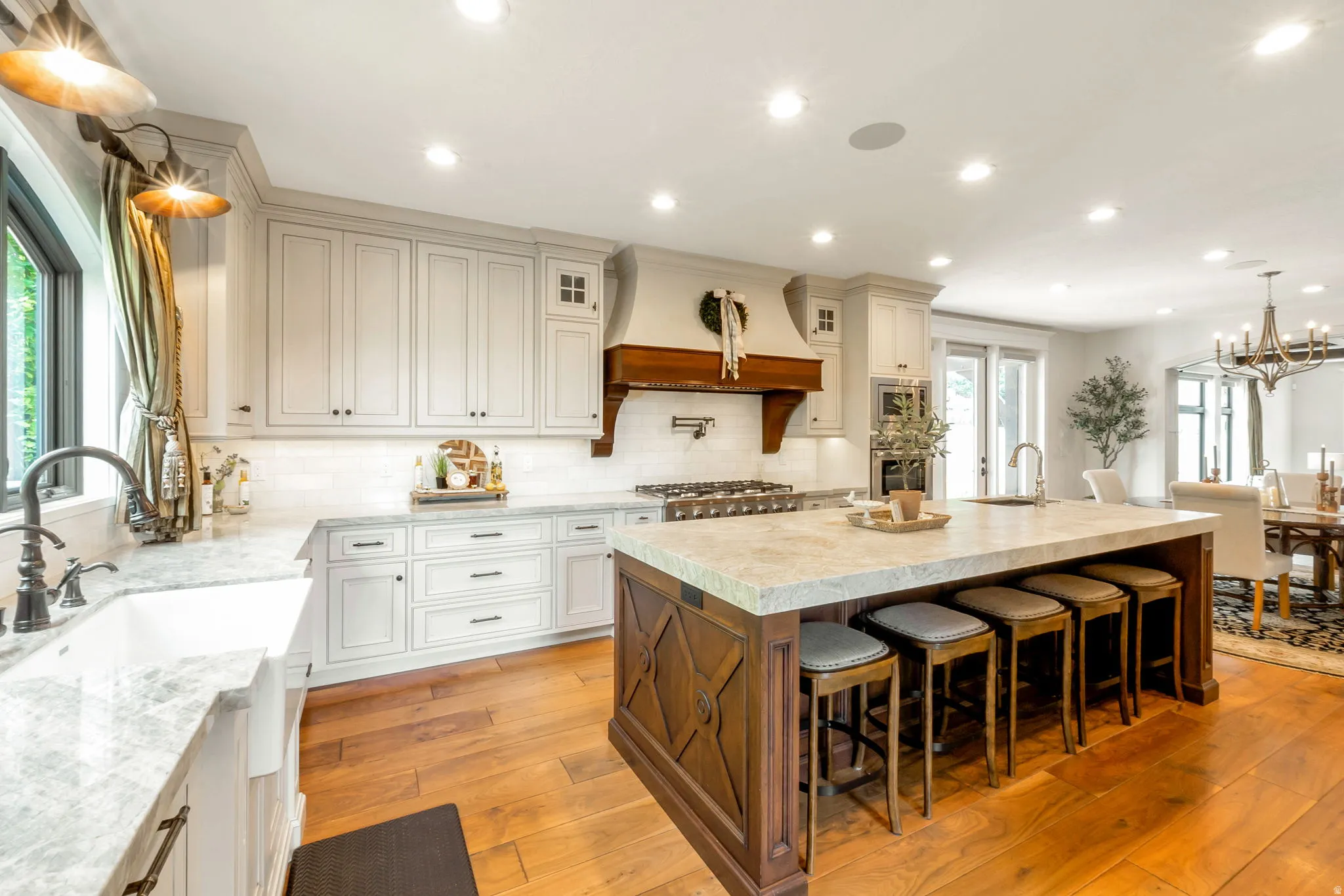 Spacious kitchen featuring a large wood-finish island with seating, light-toned cabinetry, and wood-finish flooring