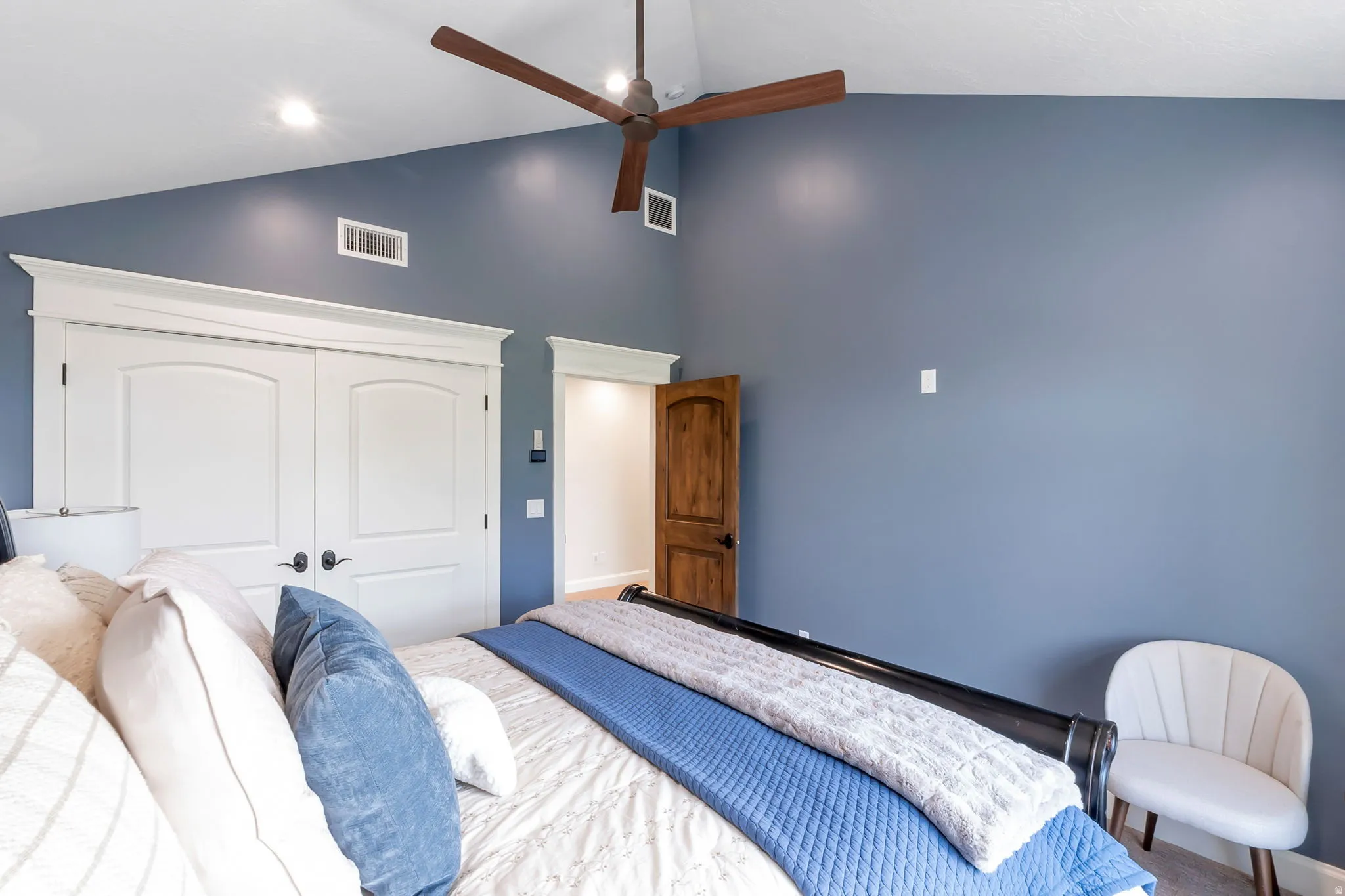 Vaulted ceiling with an overhead fan and recessed lighting, featuring a wood-finish door and white paneled closet doors with dark hardware