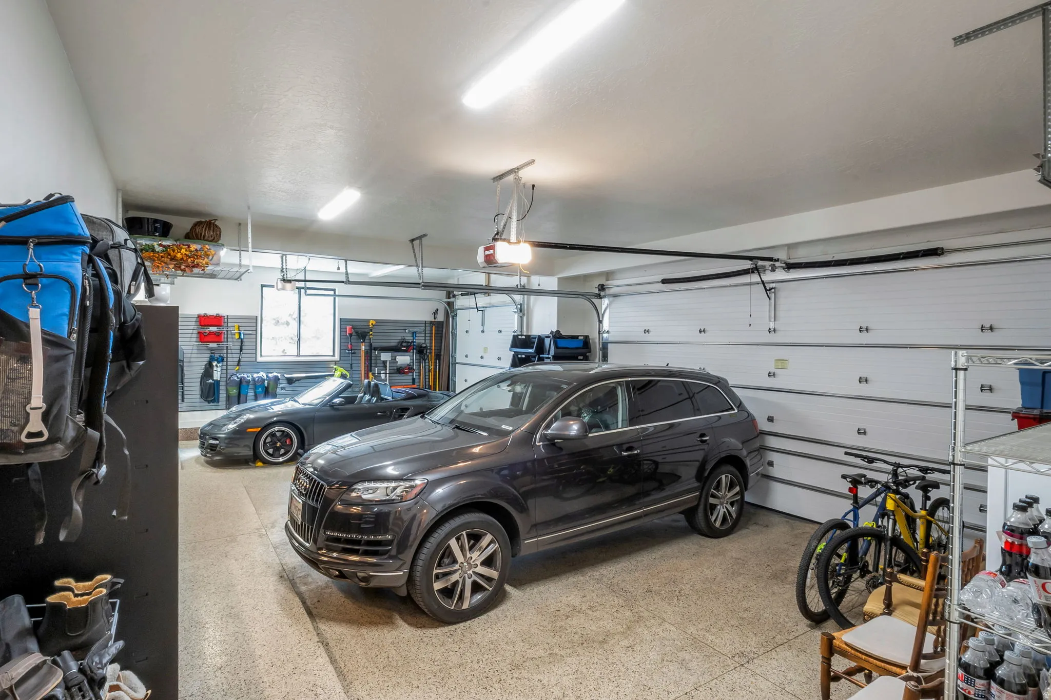 Spacious two-car garage featuring a concrete floor, white paneled garage doors, and overhead fluorescent lighting