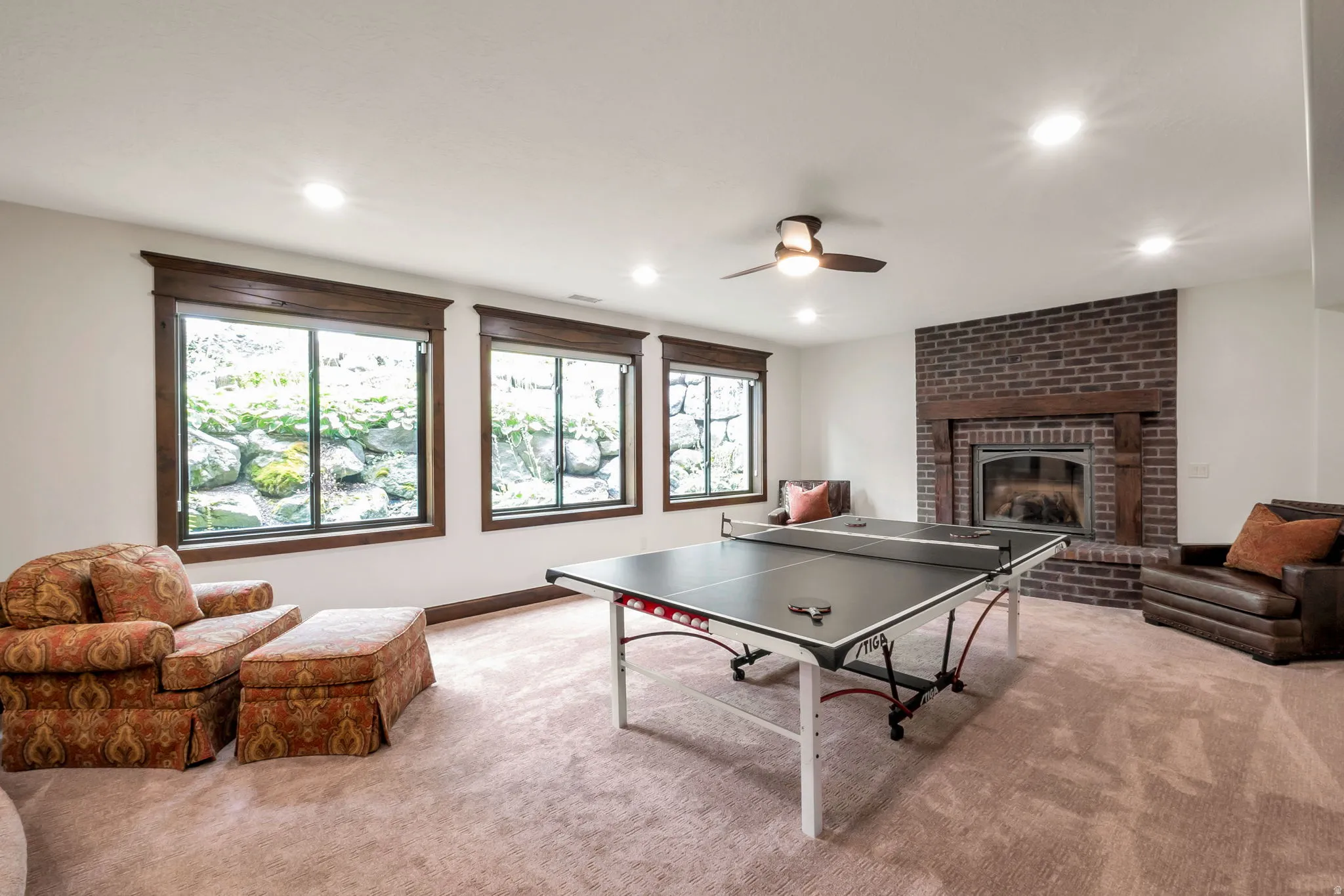 Spacious recreation room featuring recessed lighting, a ceiling fan, and a brick fireplace with a wood mantle