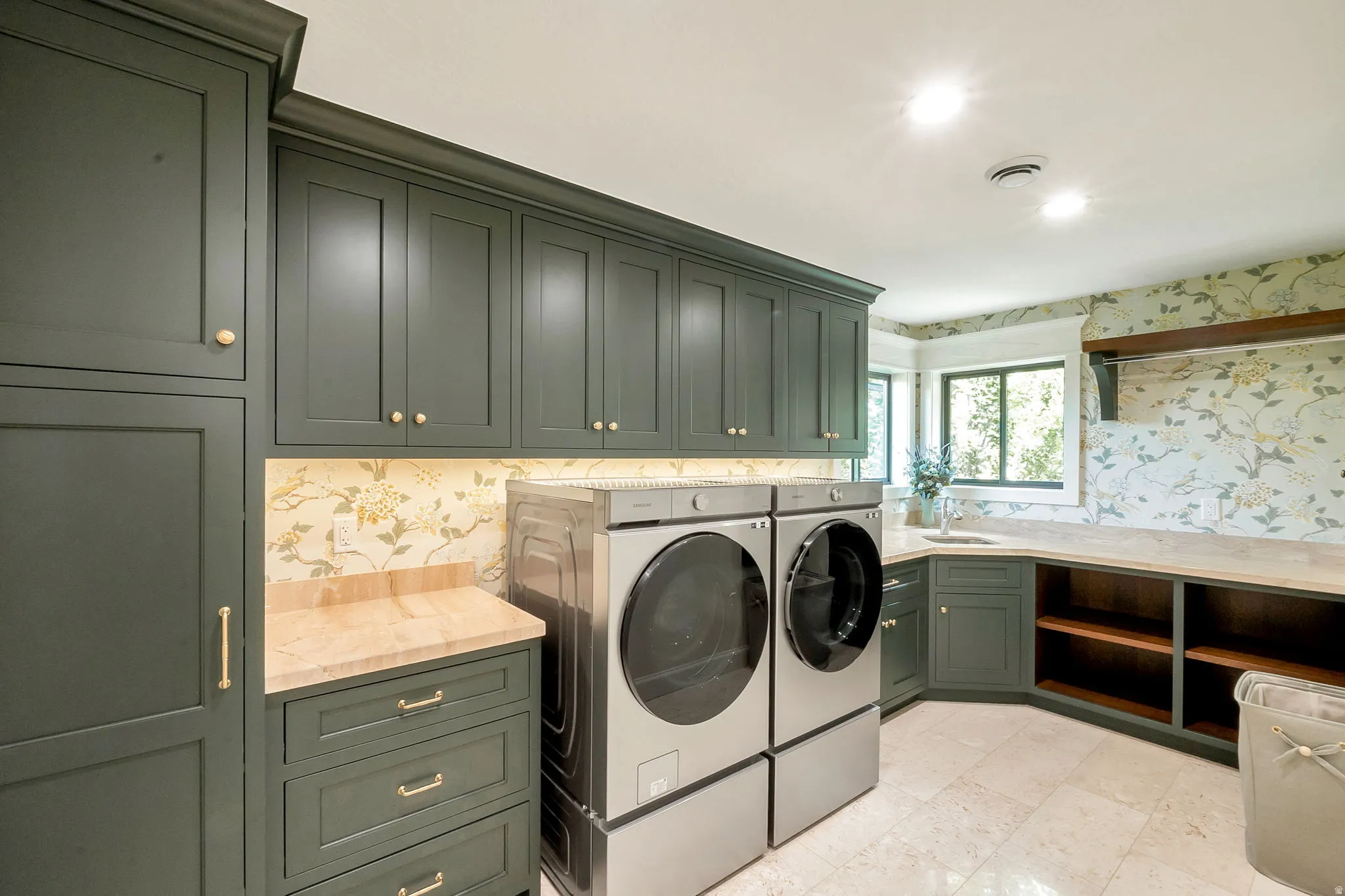 Spacious utility room featuring extensive built-in cabinetry, durable stone-finish countertops, floral pattern wall covering, and recessed lighting