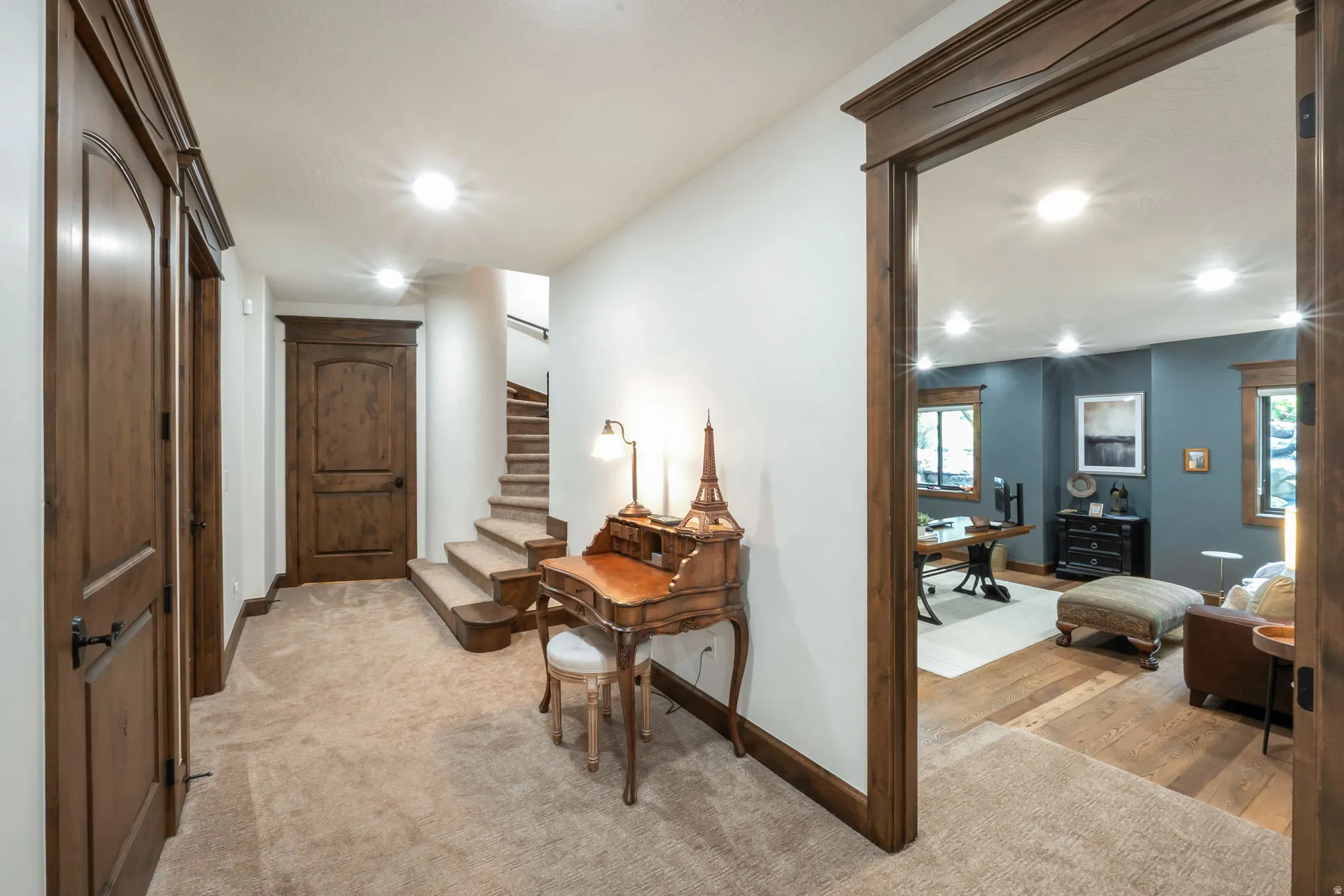 Hallway featuring plush carpeting, wood-finish doors, and matching wood trim