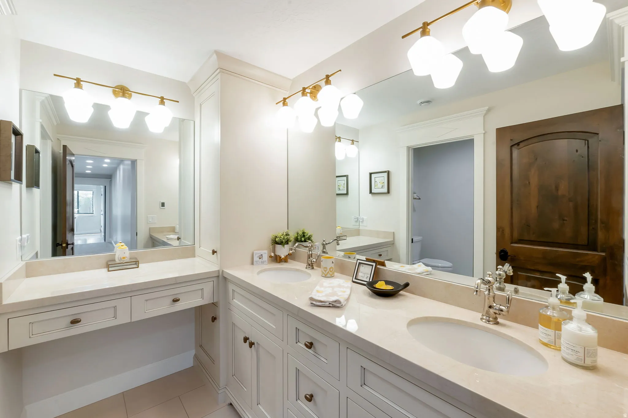 Spacious bathroom featuring a dual vanity, light-toned countertops, and custom white cabinetry