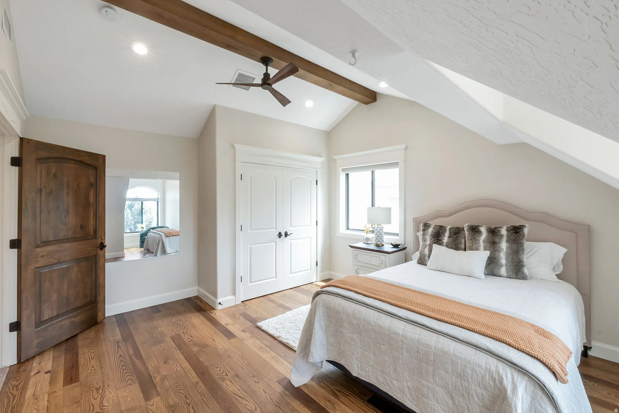Vaulted ceilings with exposed wood beams, recessed lighting, and wood-finish flooring