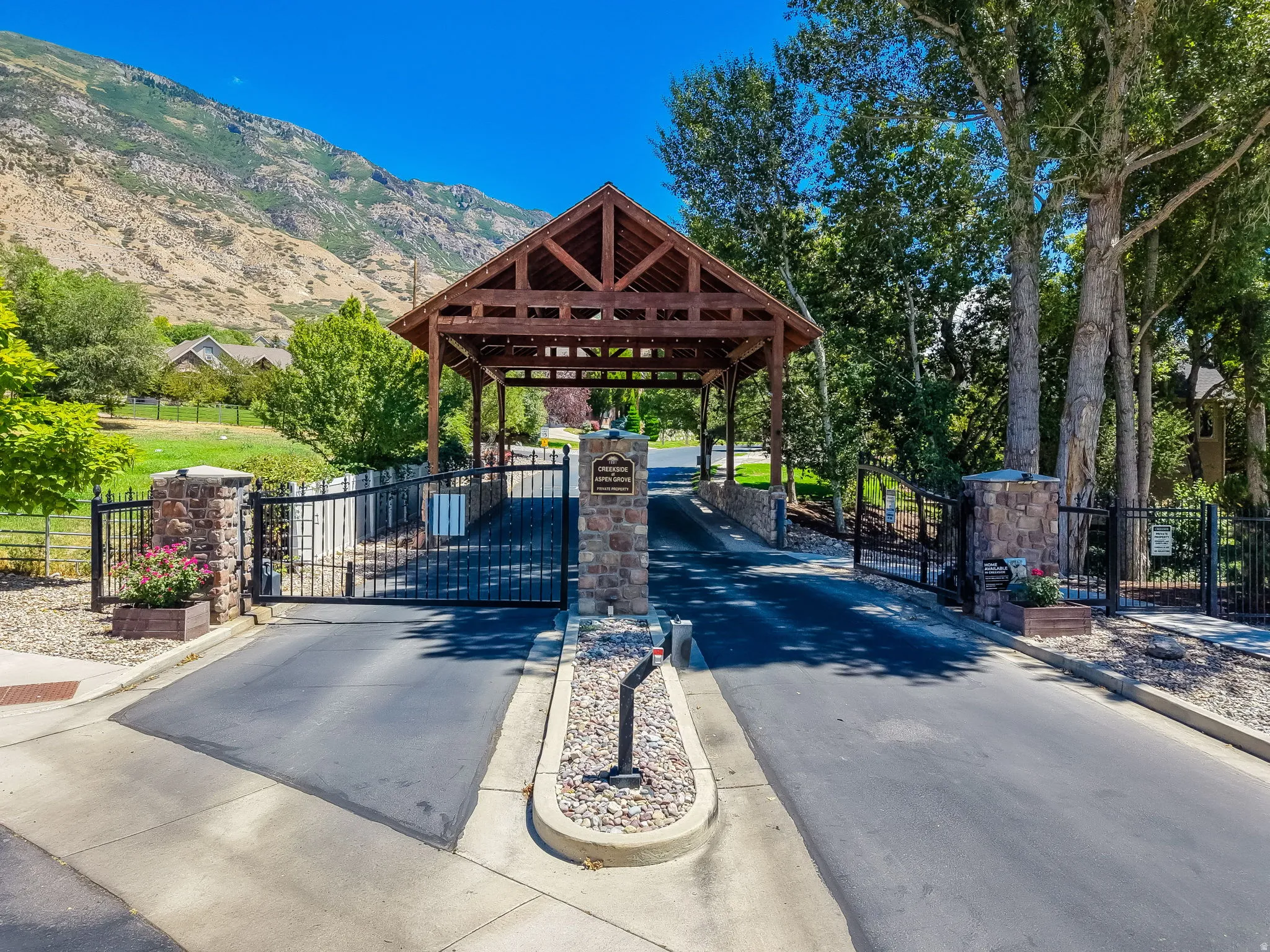 Gated entrance featuring stone pillars and a decorative wrought iron gate