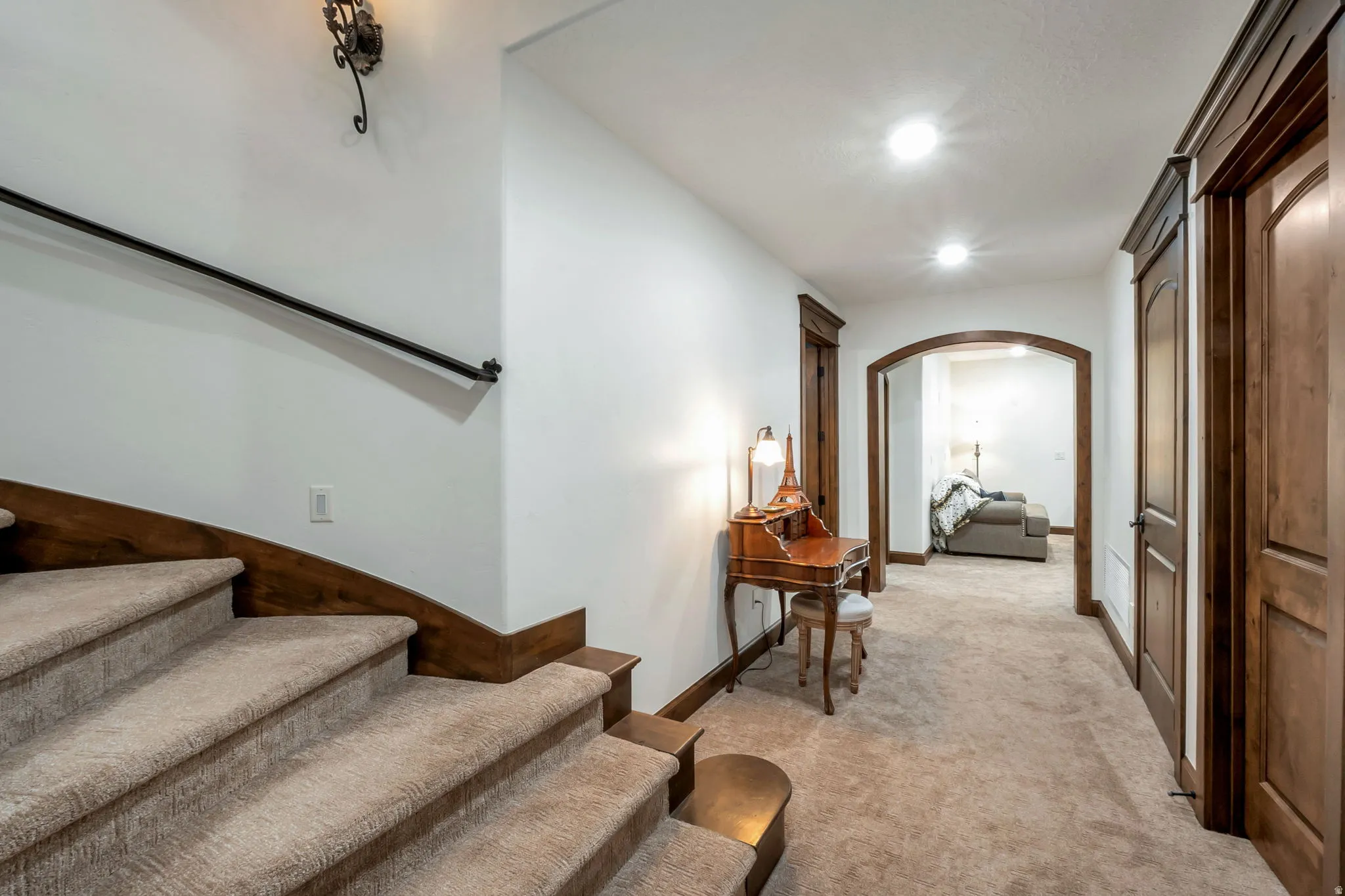 Carpeted staircase with dark wood-finish trim and black metal handrail