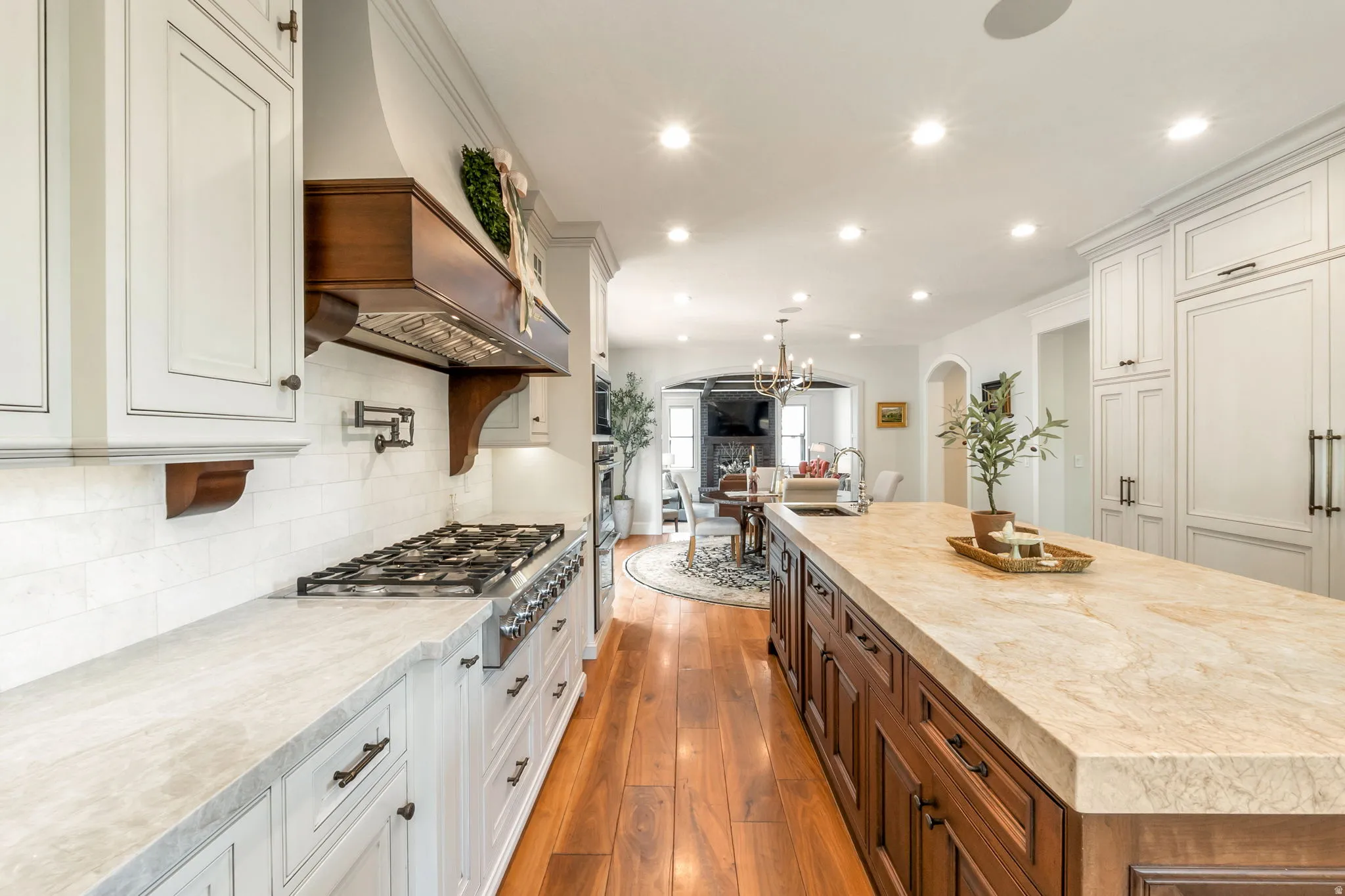 Gourmet kitchen featuring a professional-grade gas range, built-in custom hood with wood accents, and light-toned cabinetry