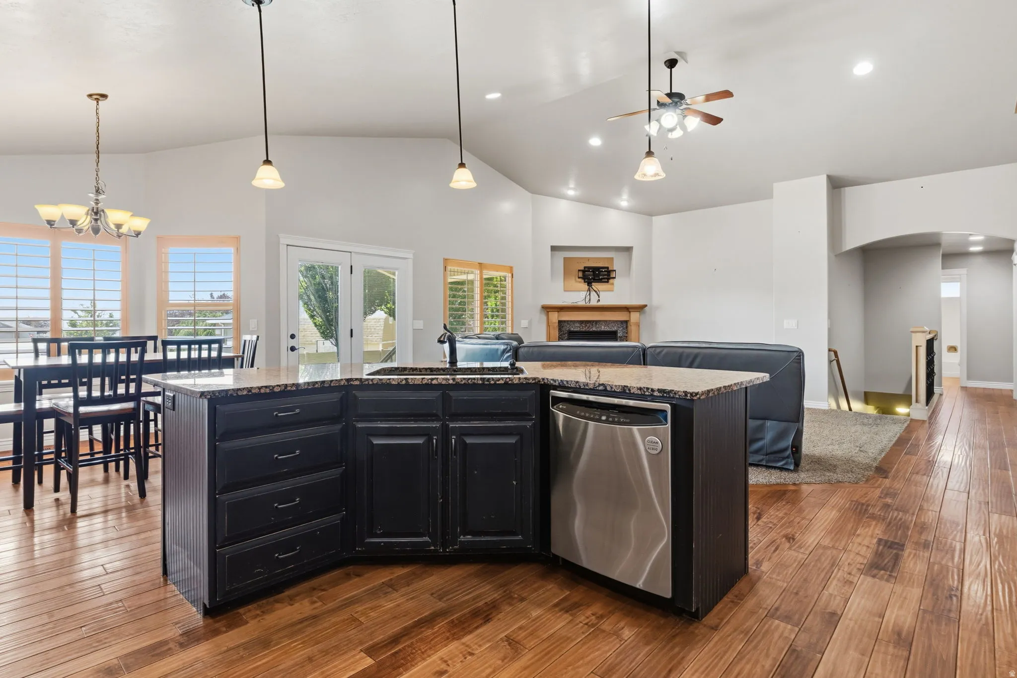 Kitchen island featuring a stainless steel dishwasher, dark cabinetry, and a stone-finish countertop