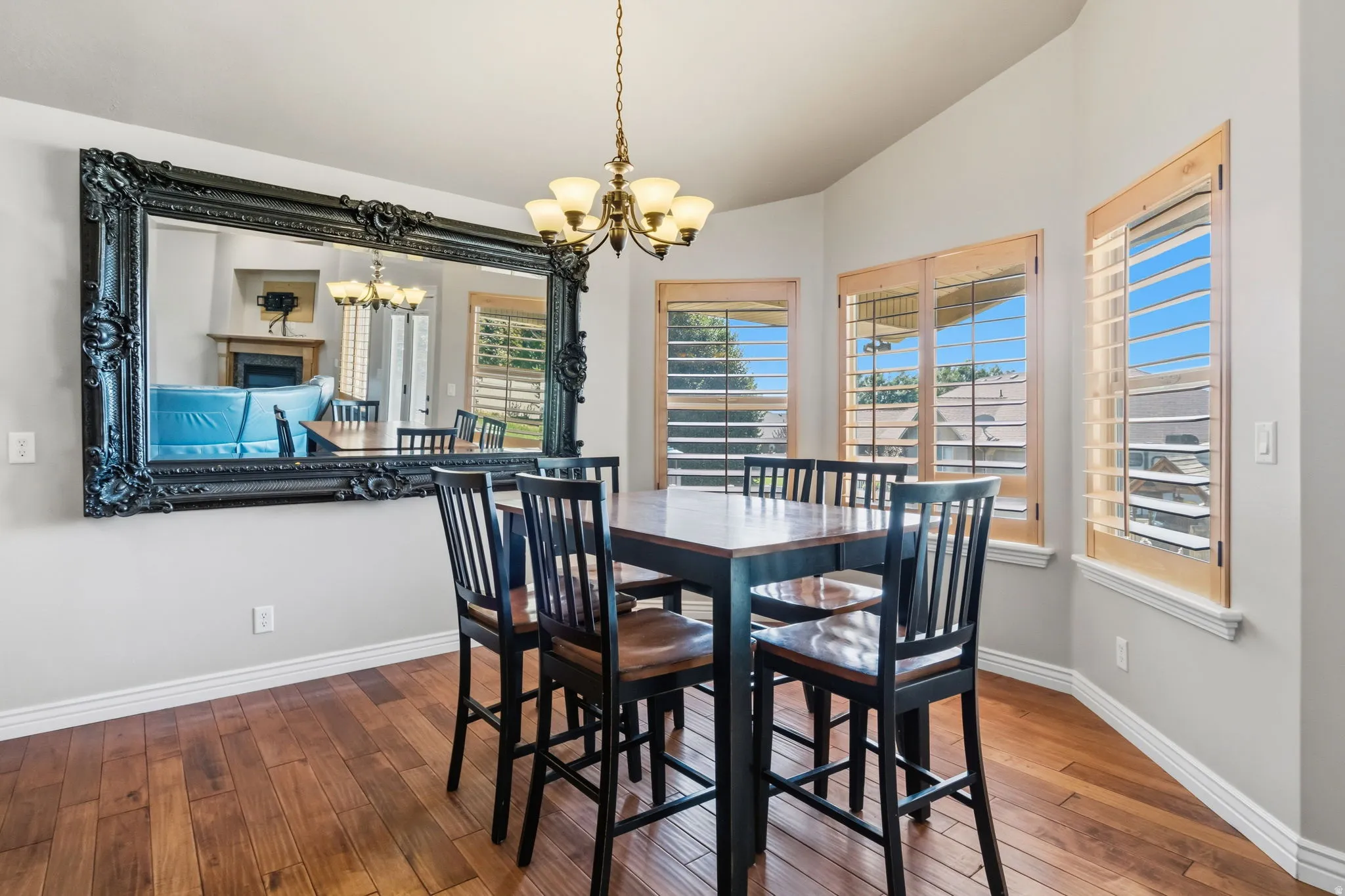 Hardwood-style flooring throughout a dining area featuring a bronze chandelier with frosted glass shades