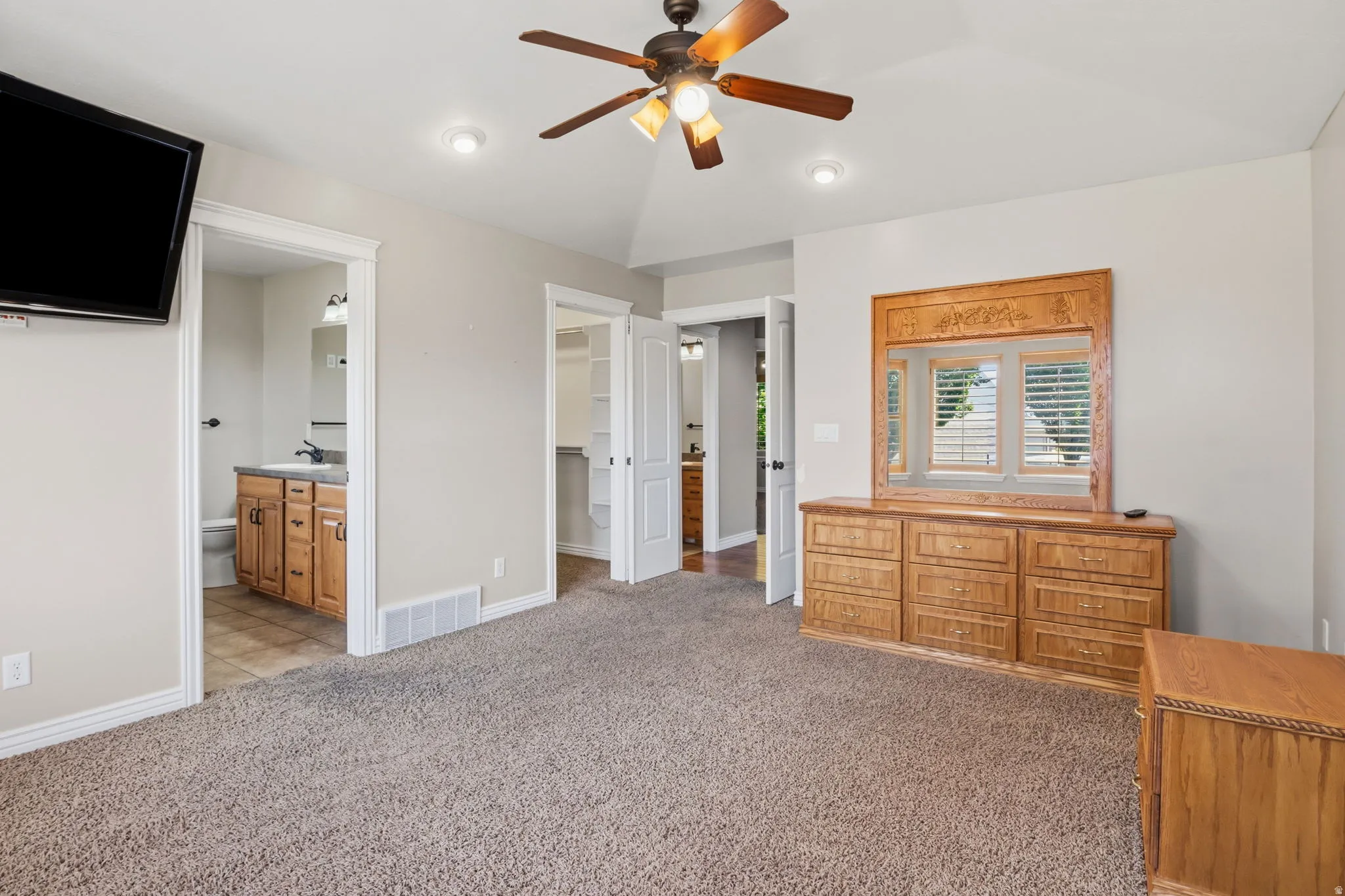 Carpeted room with vaulted ceiling and a ceiling fan
