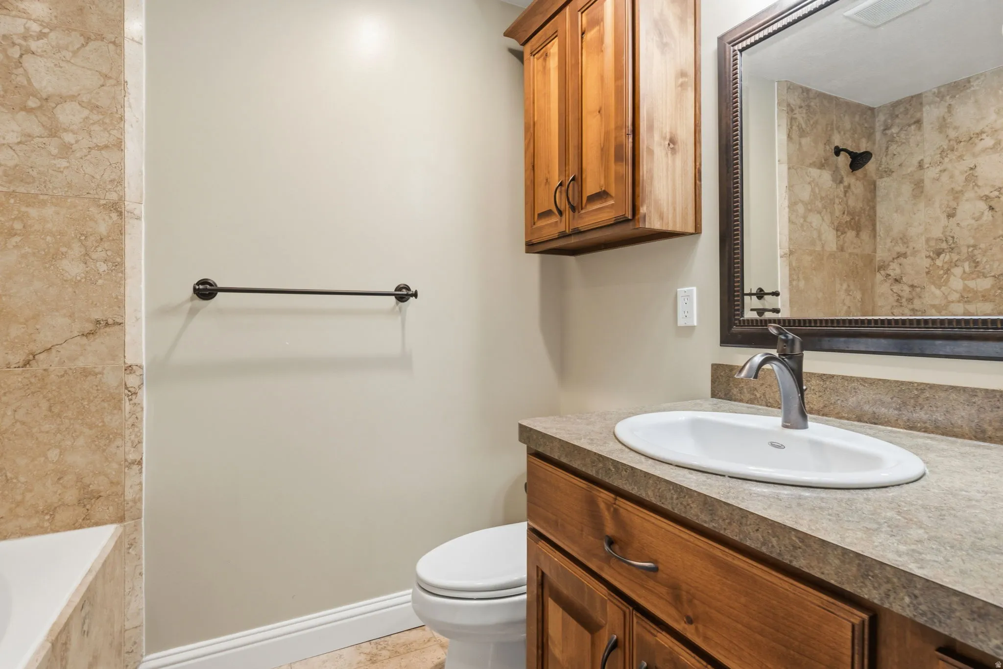 Bathroom featuring a wood-finish vanity with an integrated sink and a neutral-toned countertop