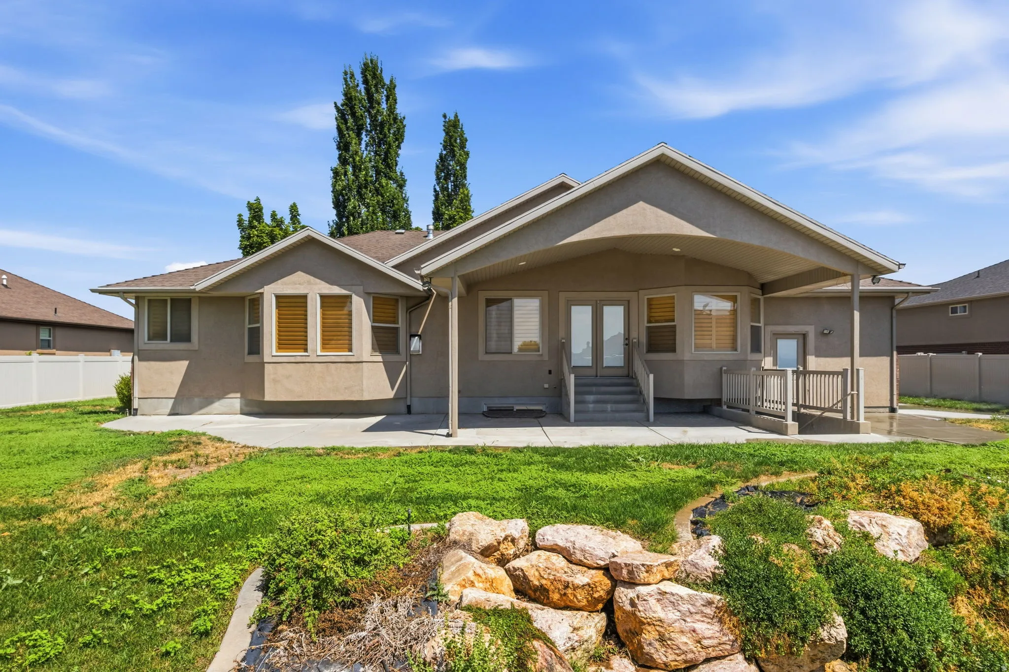 Rear exterior featuring a covered patio, dual glass-paneled doors, and a concrete patio