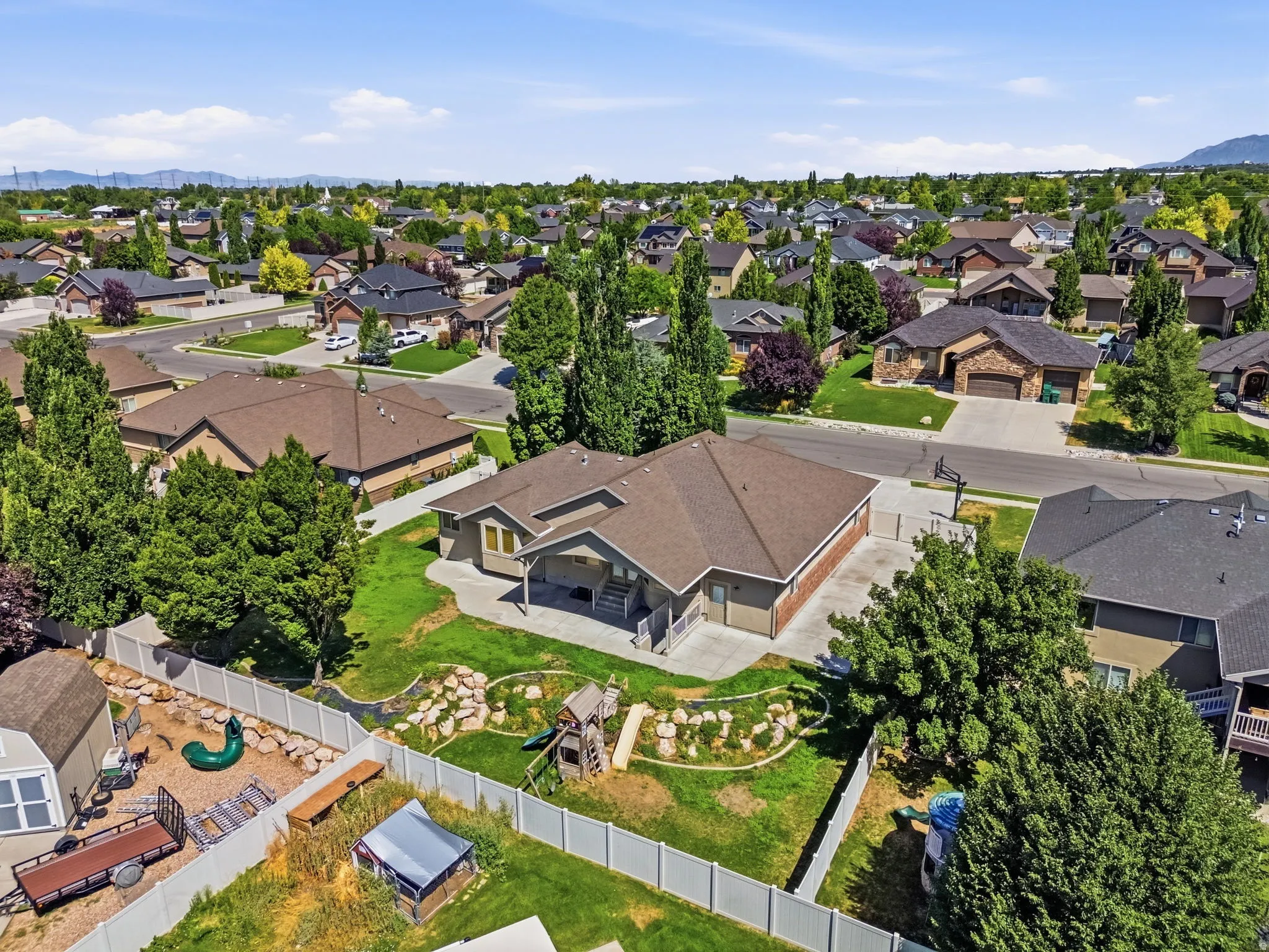 Property features a neutral-toned exterior, a multi-car driveway, and a fenced backyard with a playset