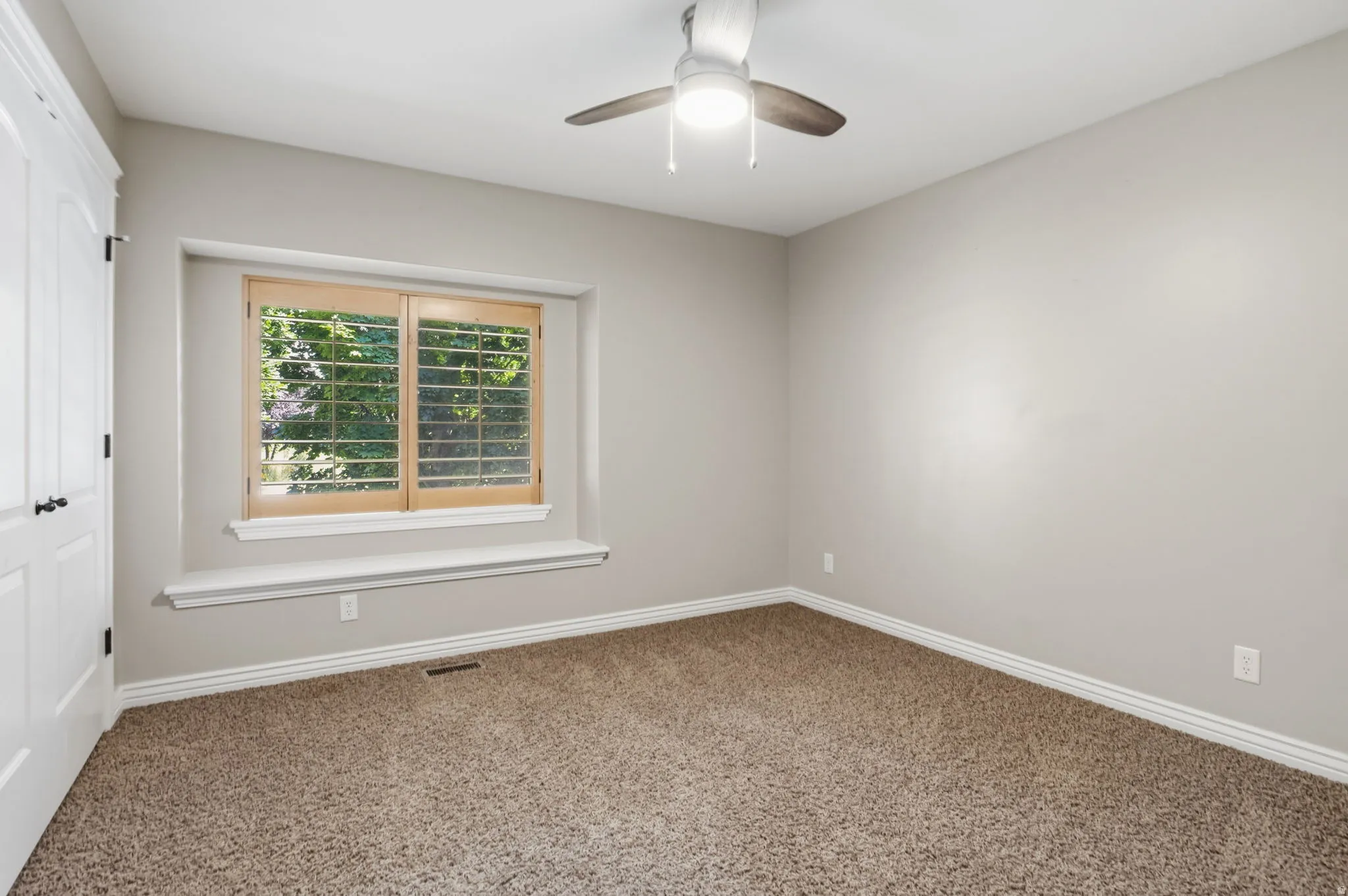 Carpeted room featuring a ceiling fan, light gray wall paint, and white trim