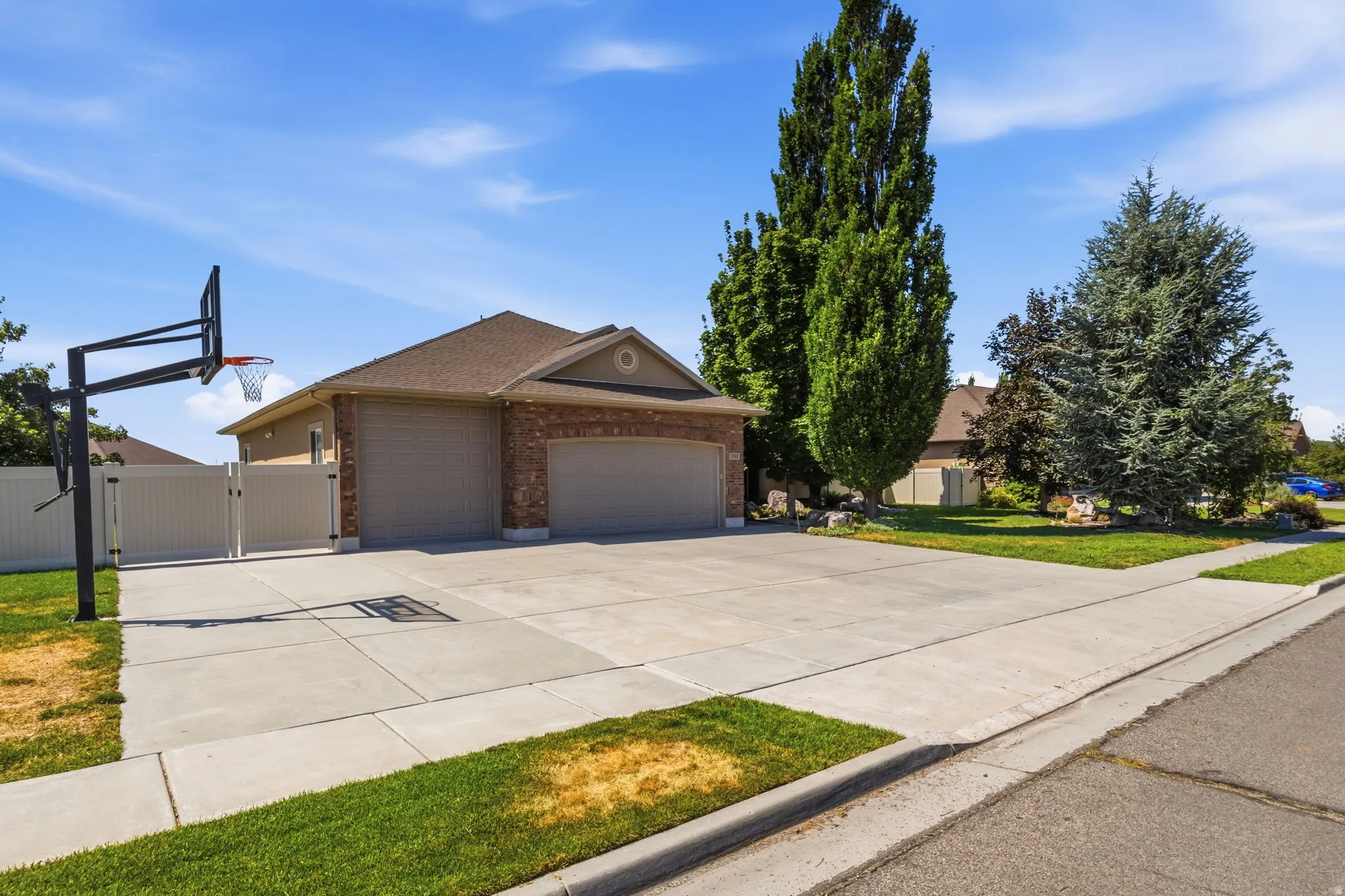 Brick facade residence with a two-car garage, concrete driveway, and mature landscaping
