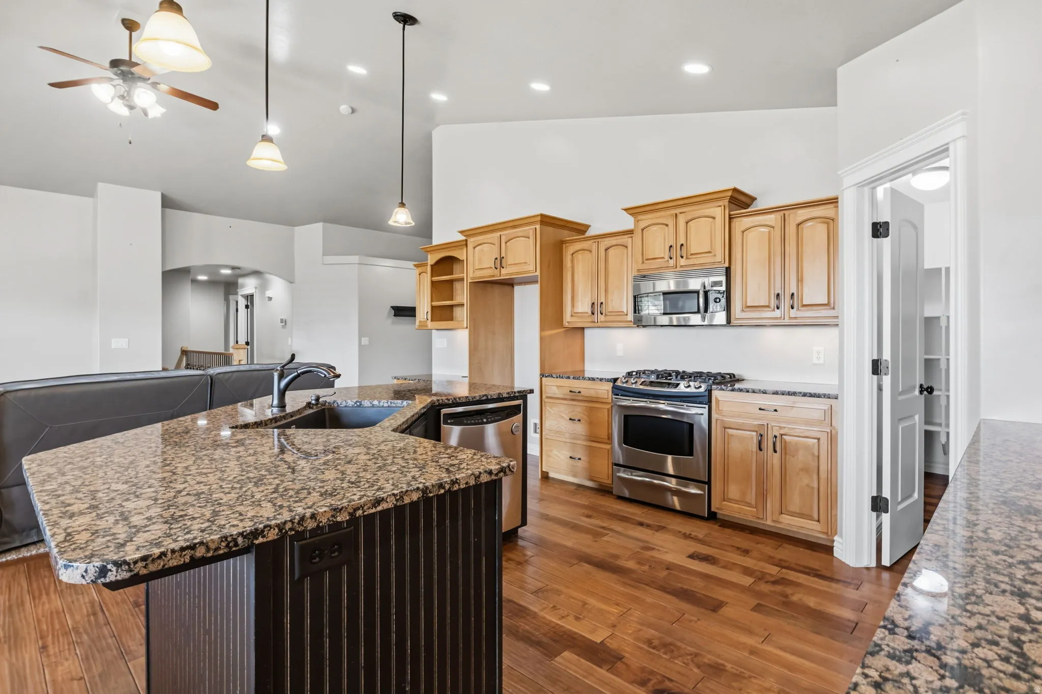 Kitchen featuring wood-finish flooring, light-toned cabinetry, stainless steel appliances, speckled countertops, and a built-in pantry