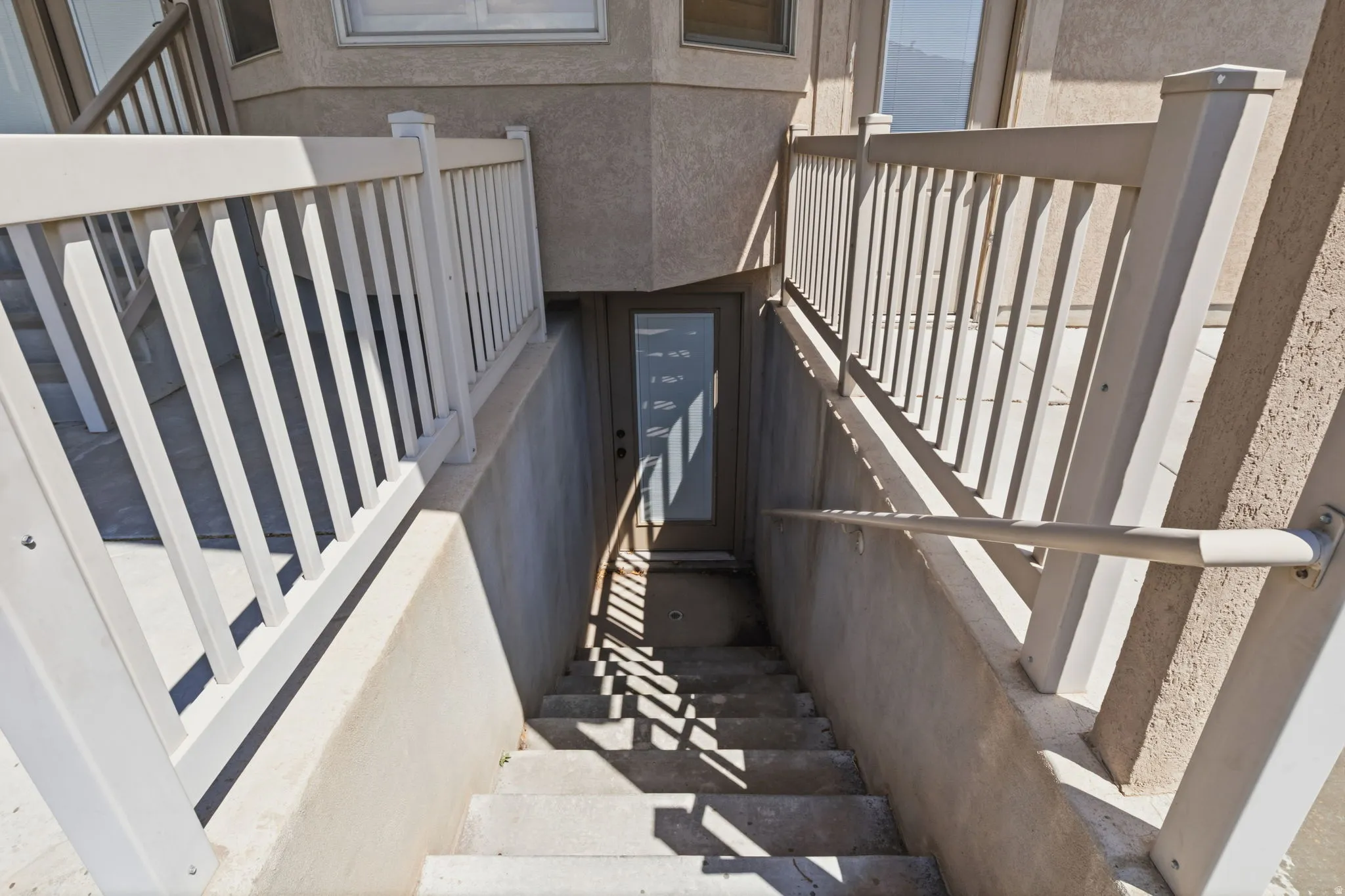 Exterior entry with concrete stairs, white railing, and a glass-paneled door