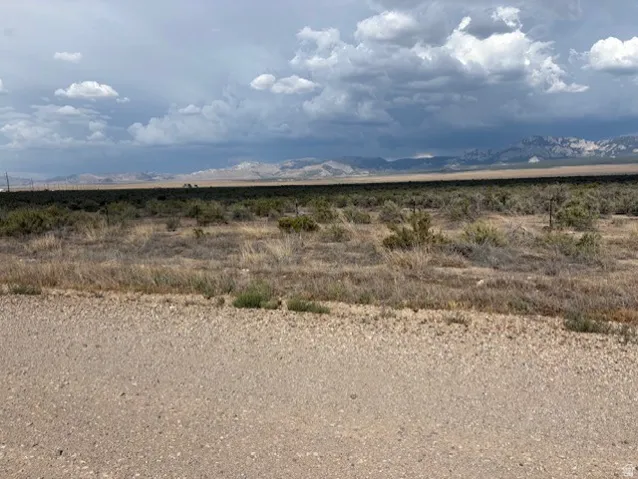 Expansive desert landscape featuring natural brush, distant mountains, and a gravel foreground