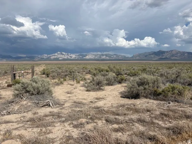 Expansive desert landscape with natural sagebrush and distant mountain ranges under a dramatic sky