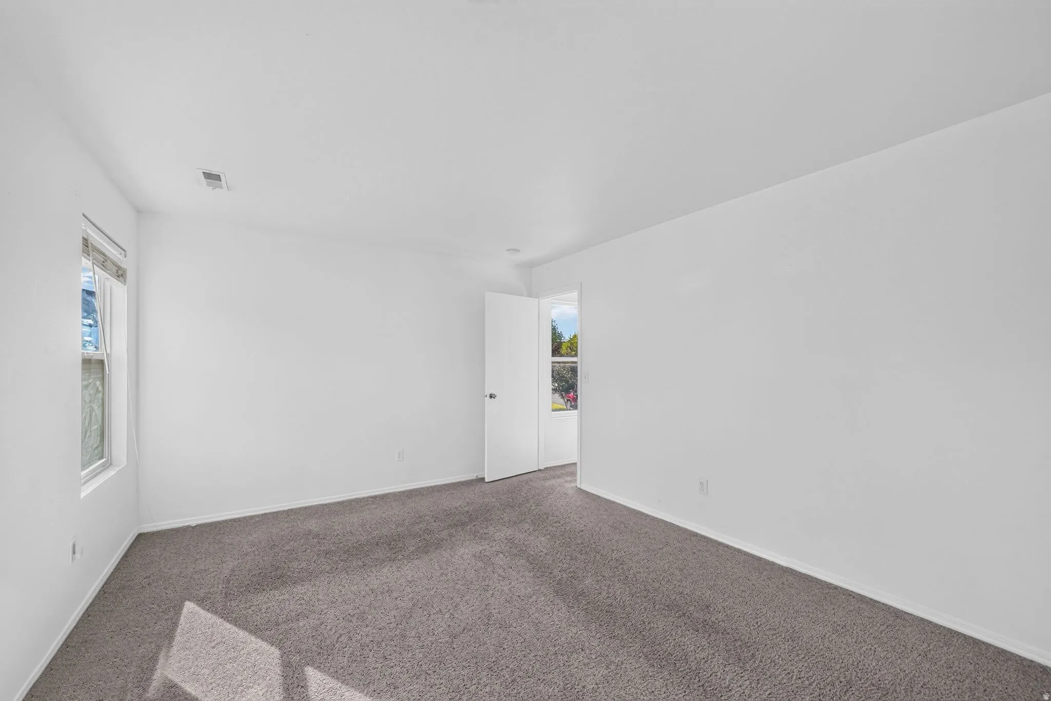 Spacious room featuring neutral carpeting, white painted walls, and a white ceiling