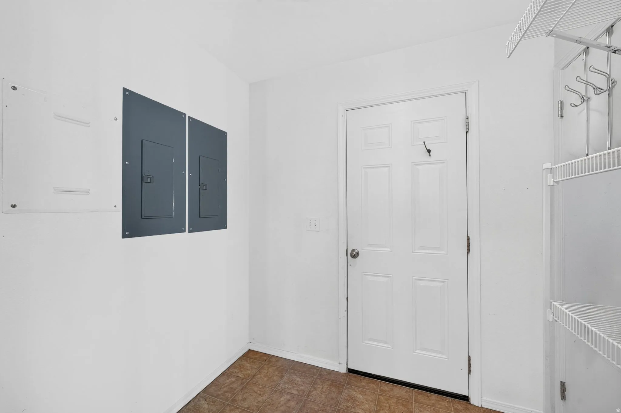 Utility room featuring a paneled door, wire shelving, and a coat rack