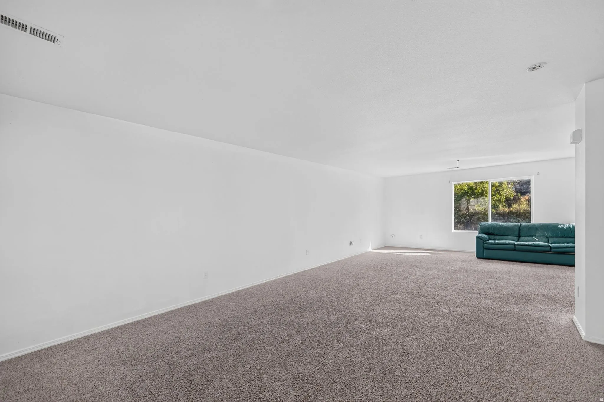 Spacious room featuring neutral carpet flooring and white painted walls