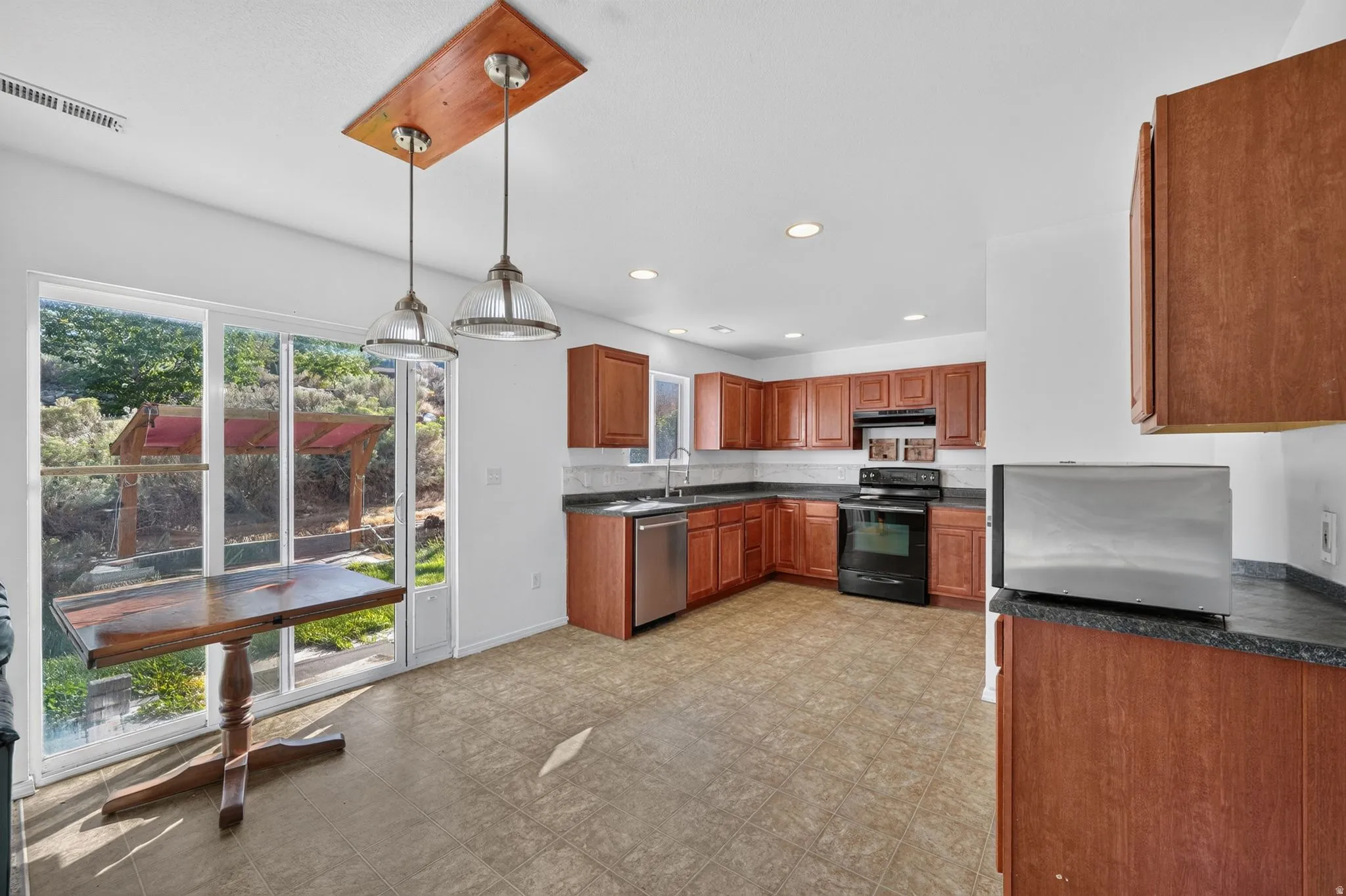 Kitchen with wood cabinetry, dark countertops, and stainless steel appliances
