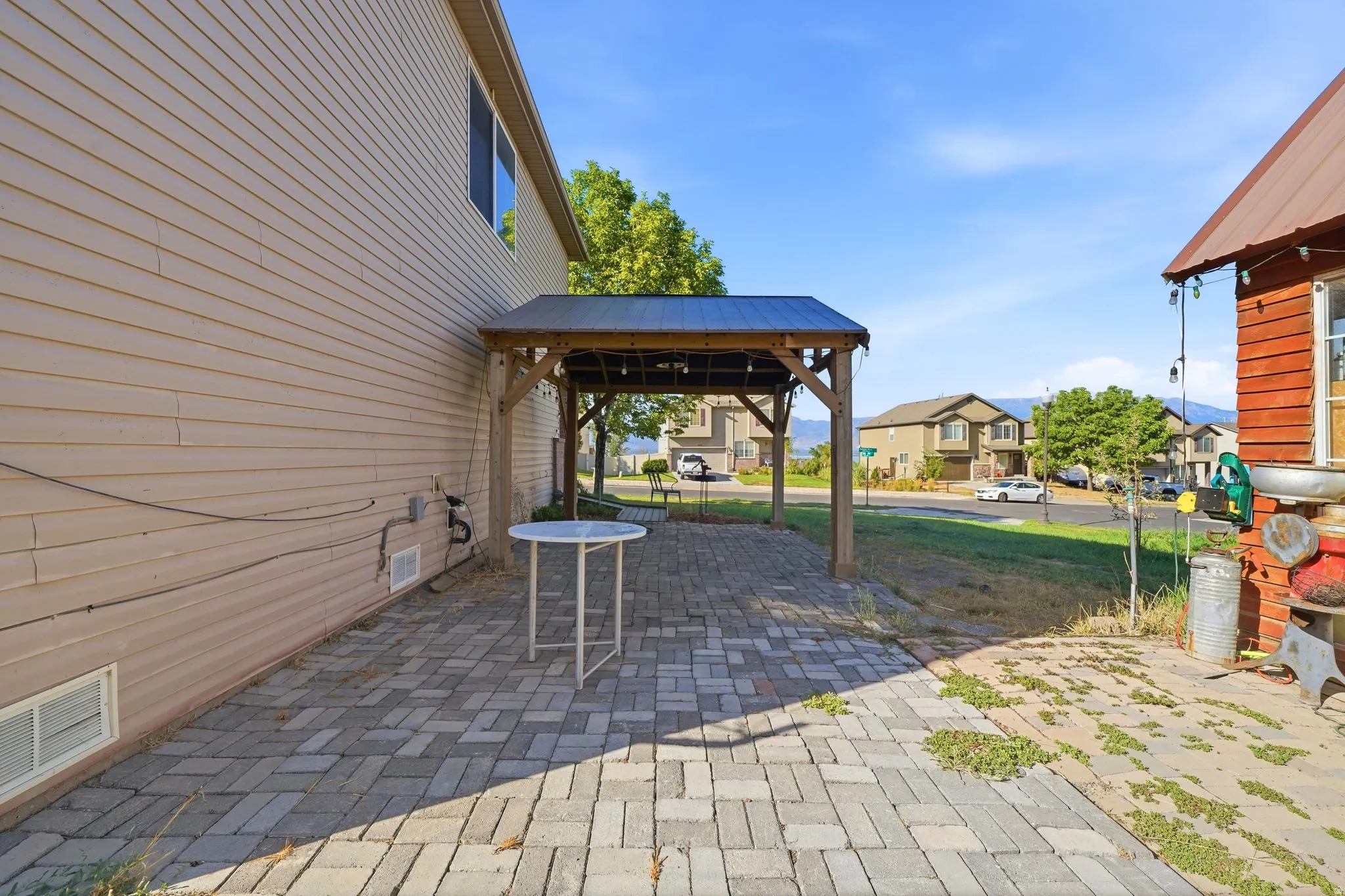 Expansive paver patio with a permanent wooden pergola featuring a dark metal roof