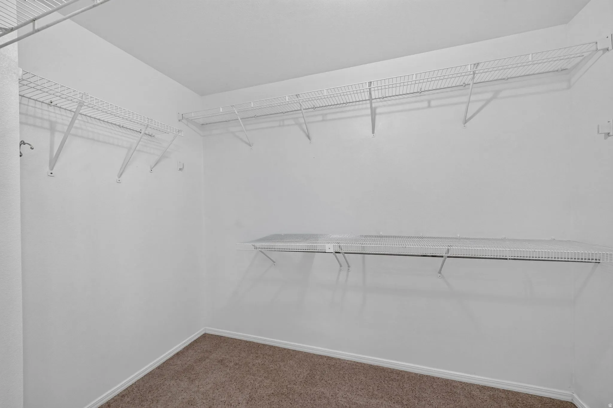 Walk-in closet featuring white wire shelving and hanging rods