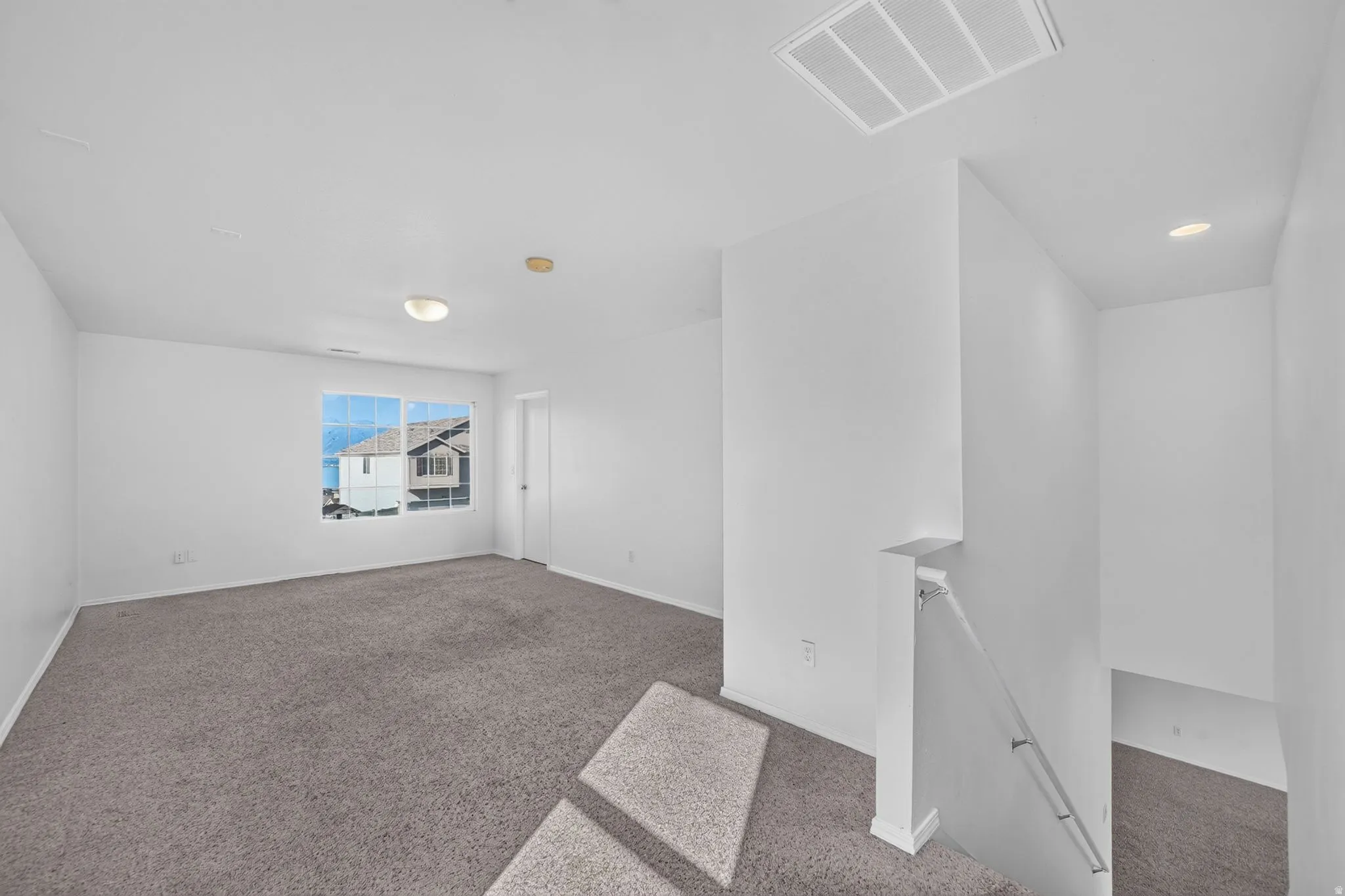 Open concept room with gray carpet flooring and bright white walls