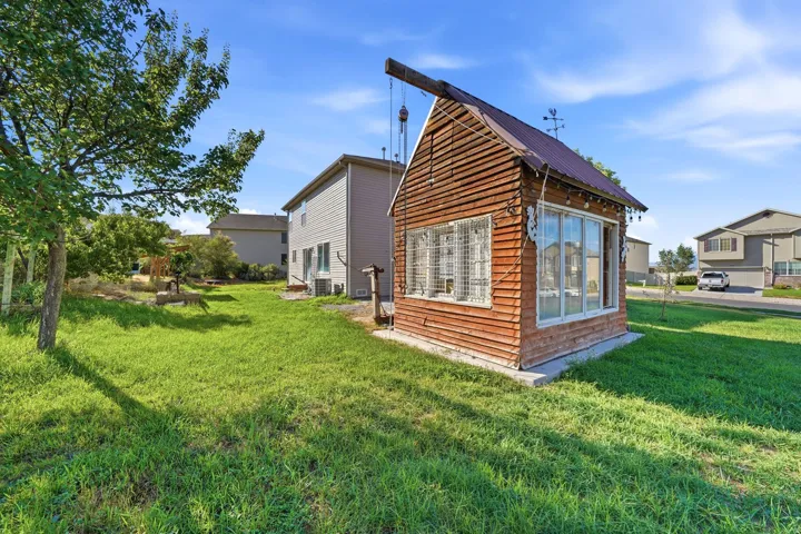 Exterior shed featuring horizontal wood siding, a metal roof, and multiple window panels