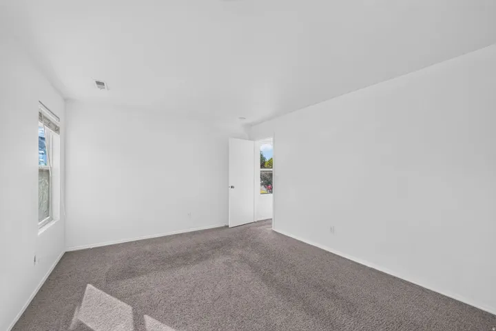 Spacious room featuring neutral carpeting, white painted walls, and a white ceiling