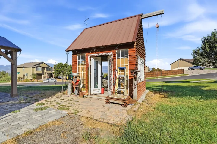 Freestanding outbuilding with a brown metal roof and cedar-style siding