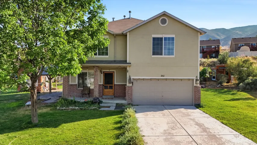 Two-story residence featuring a brick and stucco exterior, an attached two-car garage, and a covered front porch