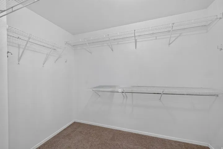 Walk-in closet featuring white wire shelving and hanging rods