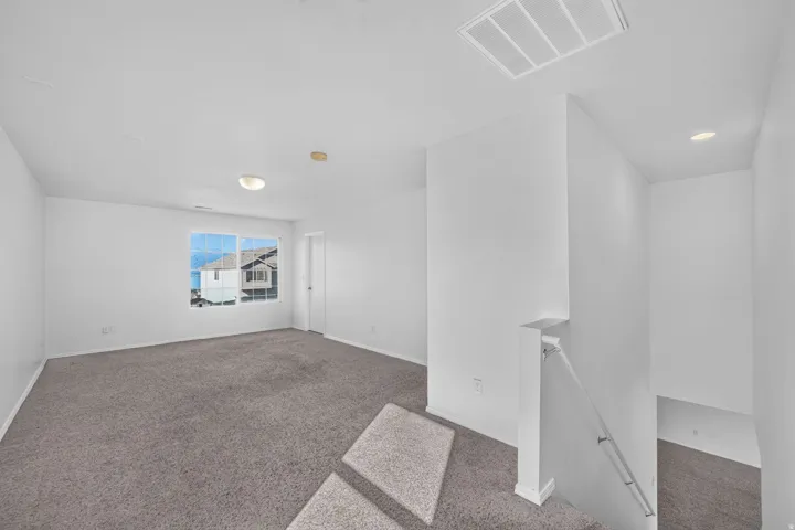 Open concept room with gray carpet flooring and bright white walls