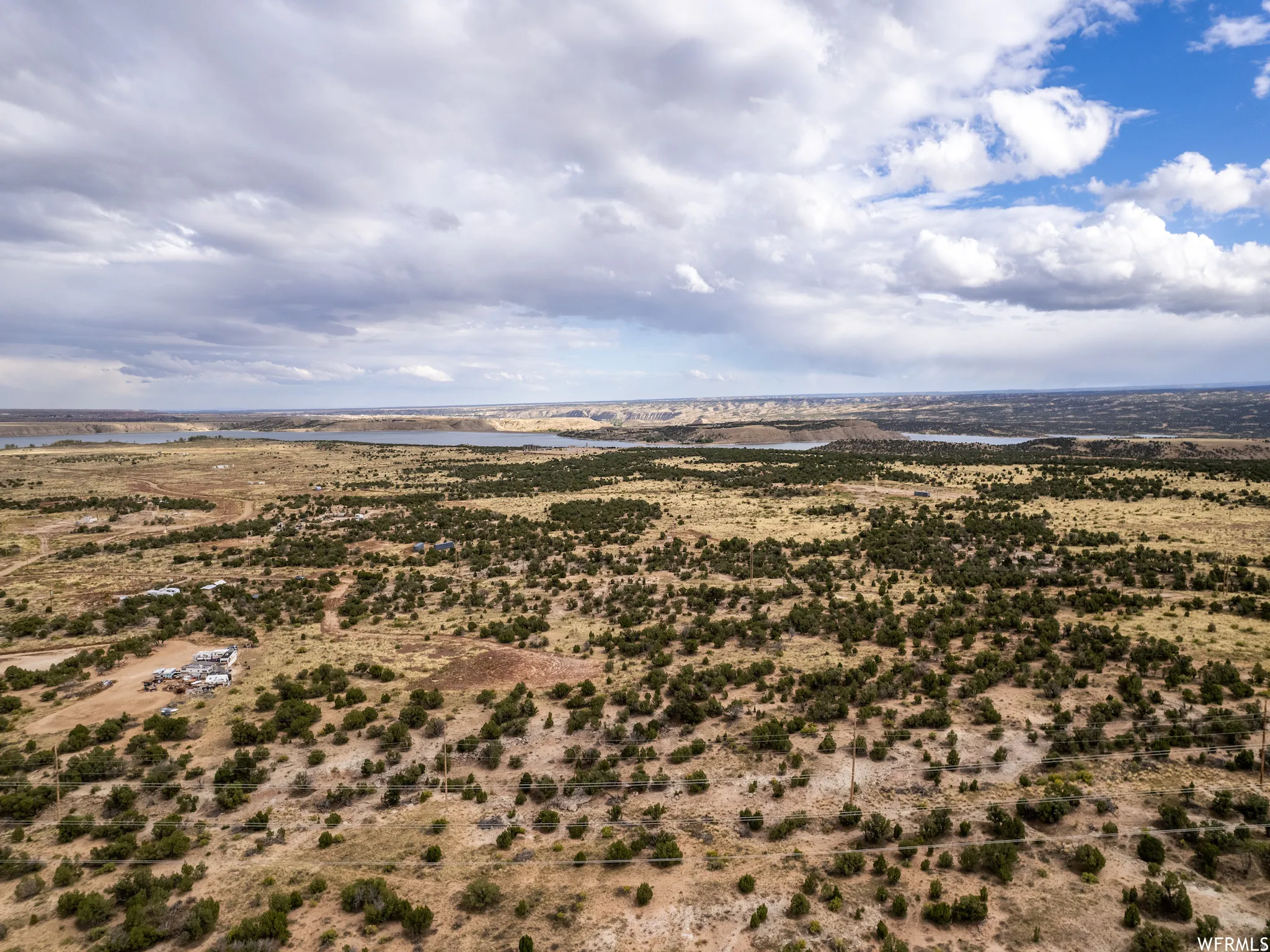 Expansive desert landscape featuring scattered green foliage and distant bodies of water